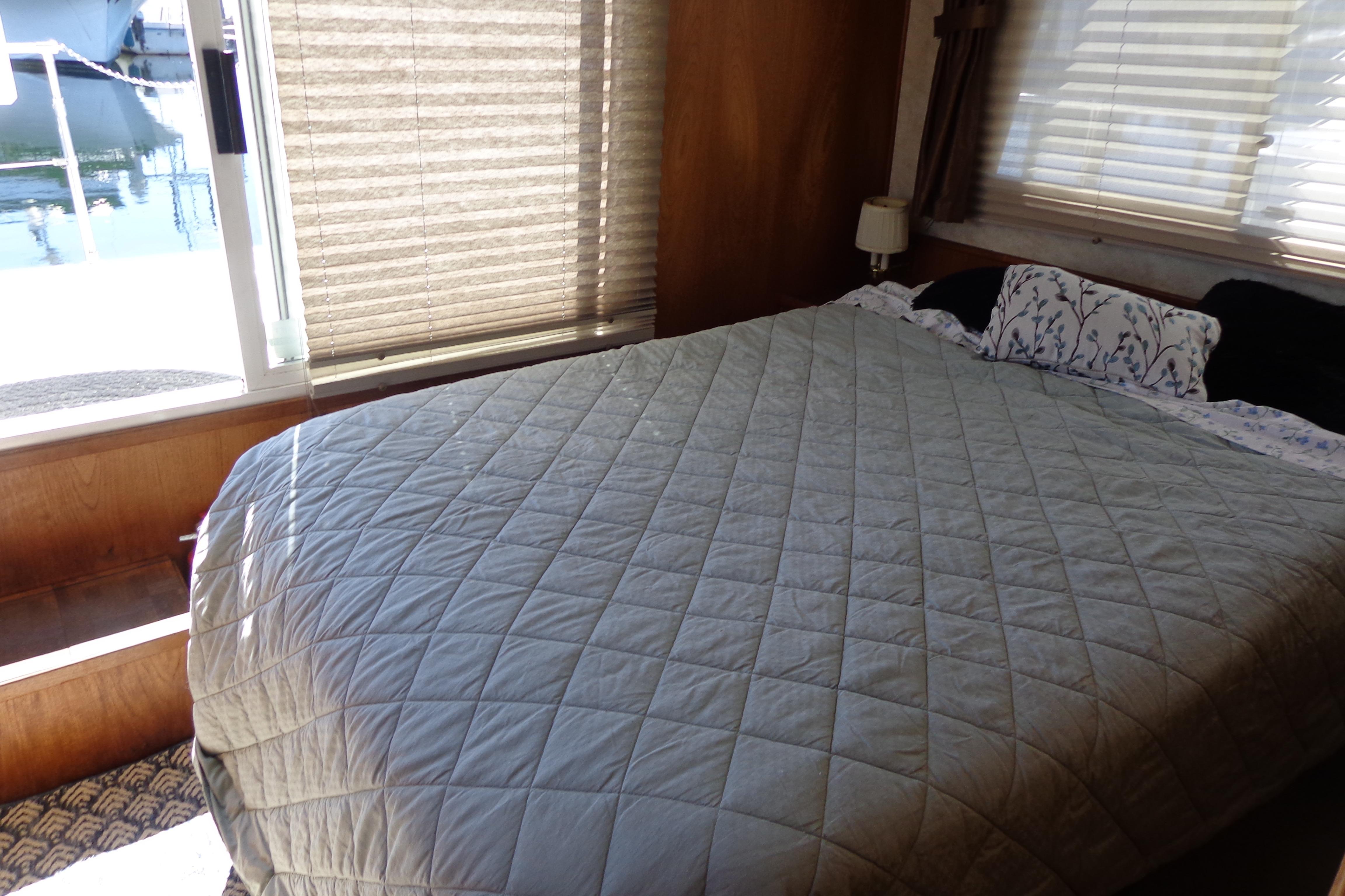 Cozy bedroom interior of 1992 Cruise-A-Home Corsair 4200 with quilted bedspread and window view.