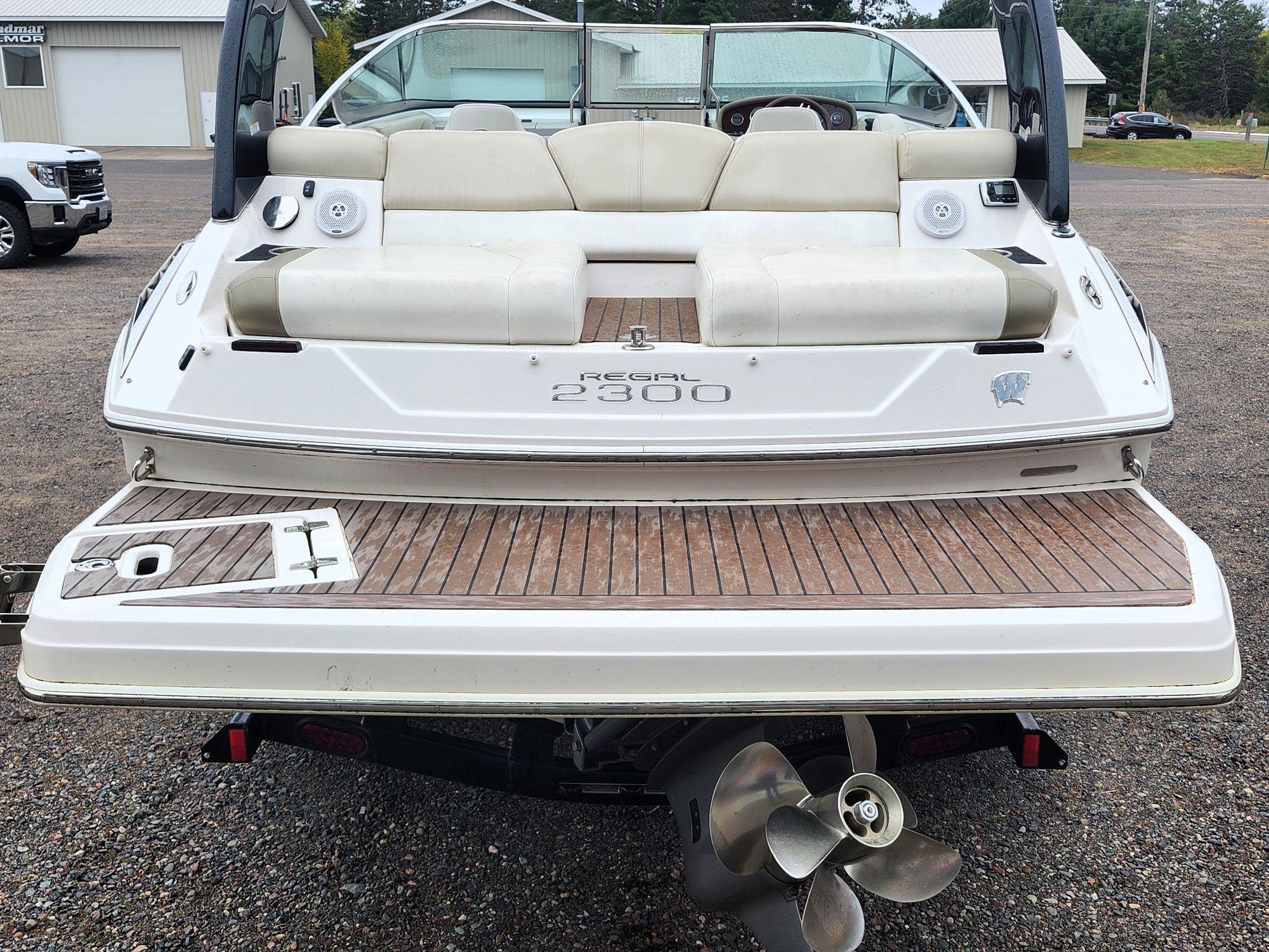 The image shows the rear of a white boat with a wooden deck and beige seats.