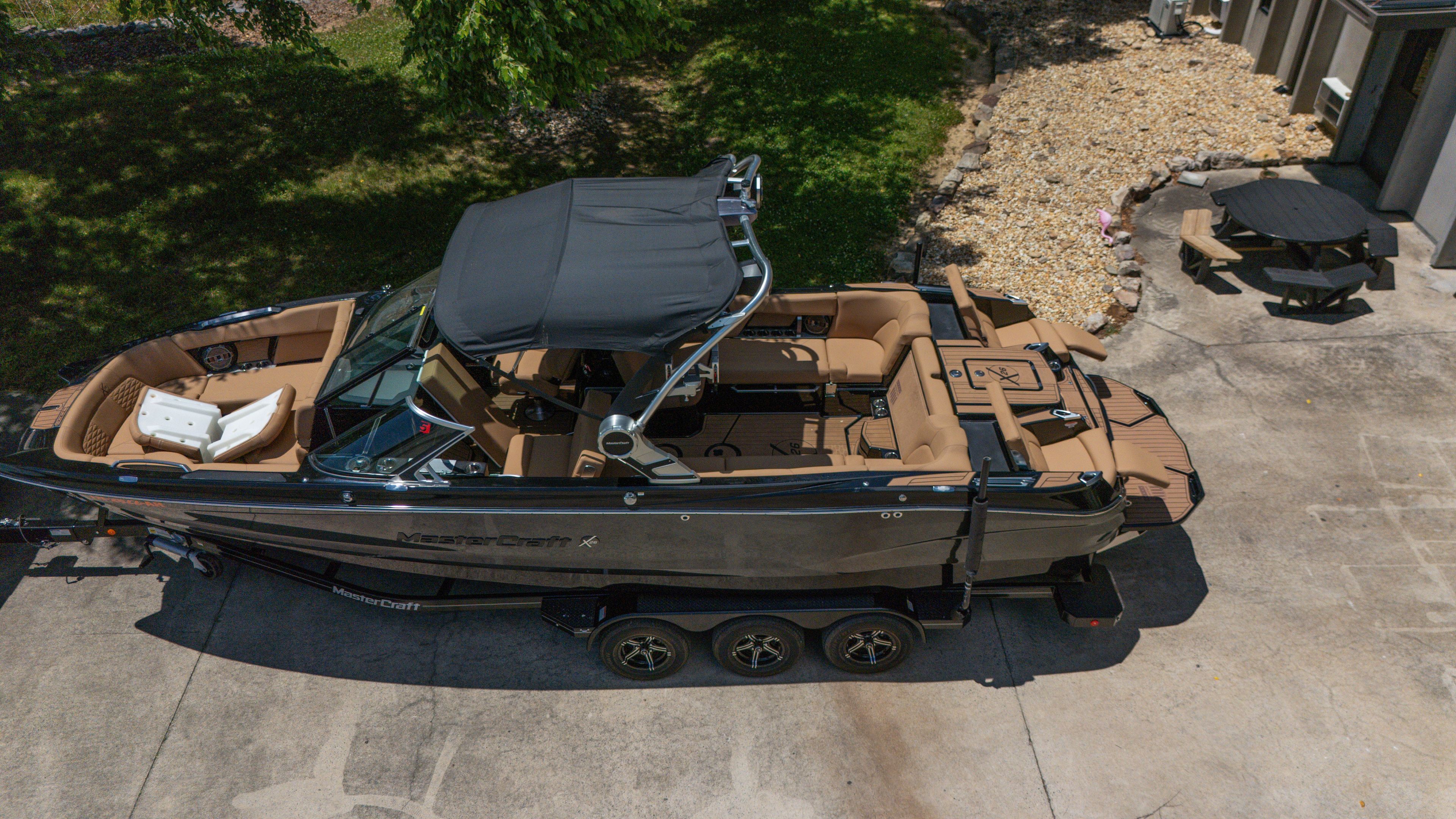 A 2021 MasterCraft X26 sits on a trailer in a driveway.