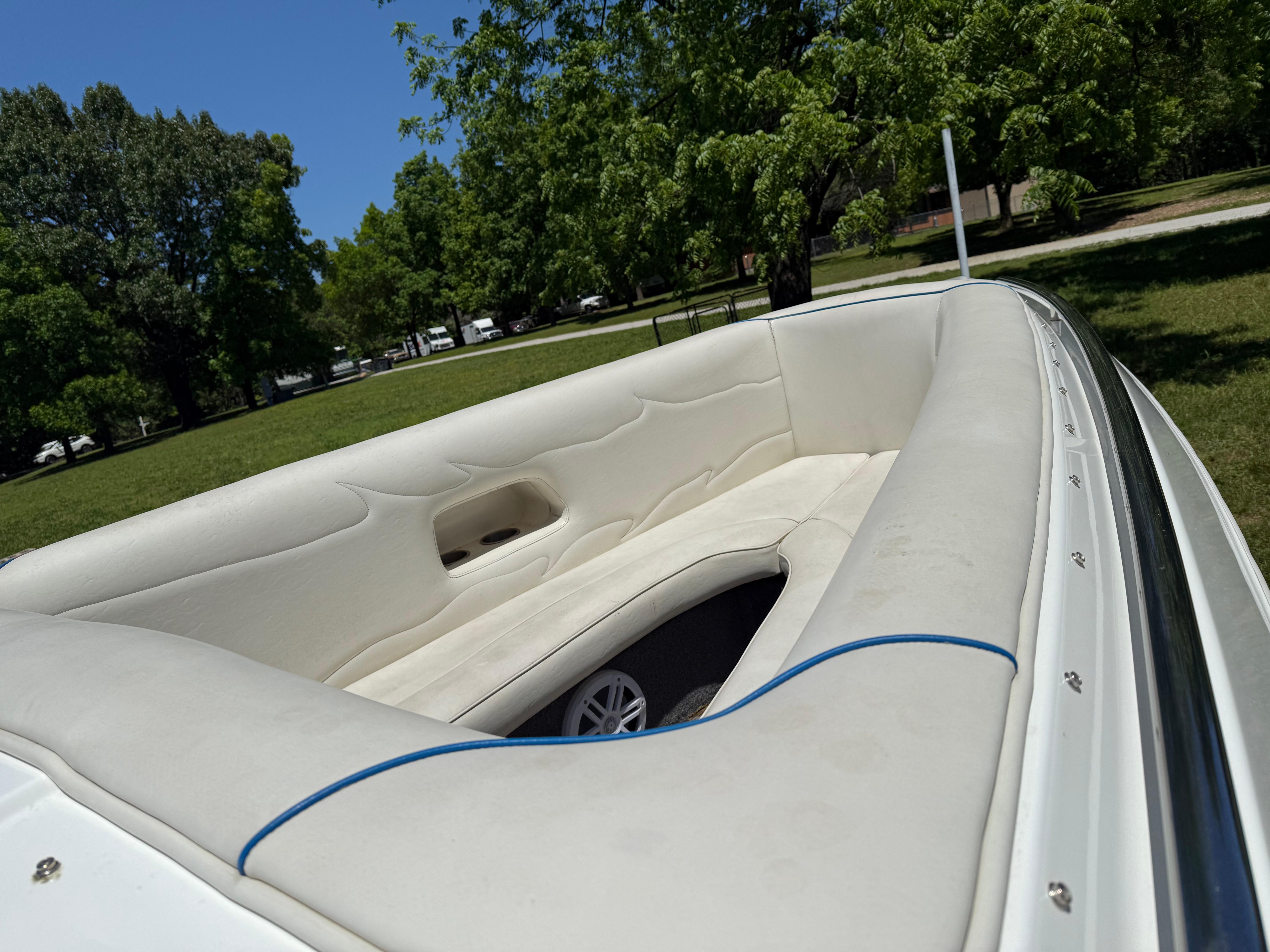 2005 Kachina Bolero boat interior with white seating, parked in a lush green park.