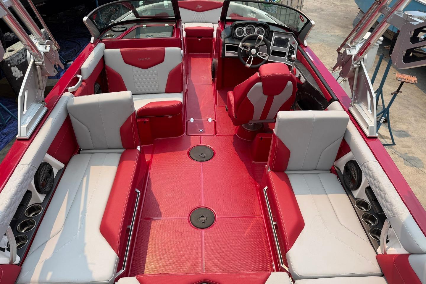 2023 MasterCraft X24 boat interior with red and white seating, modern dashboard, and spacious layout.
