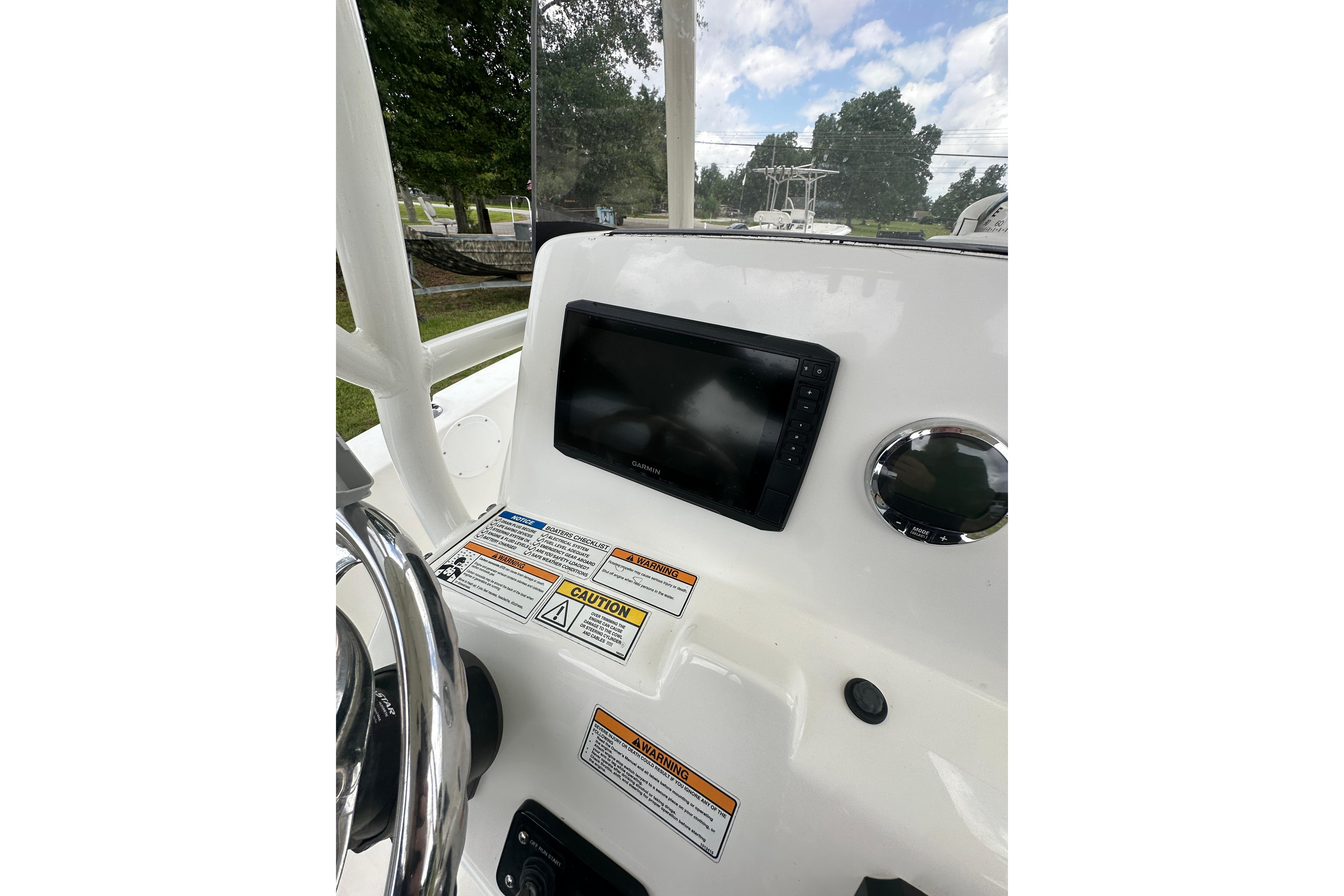 2023 NauticStar 2102 Legacy boat dashboard with Garmin display and caution labels.