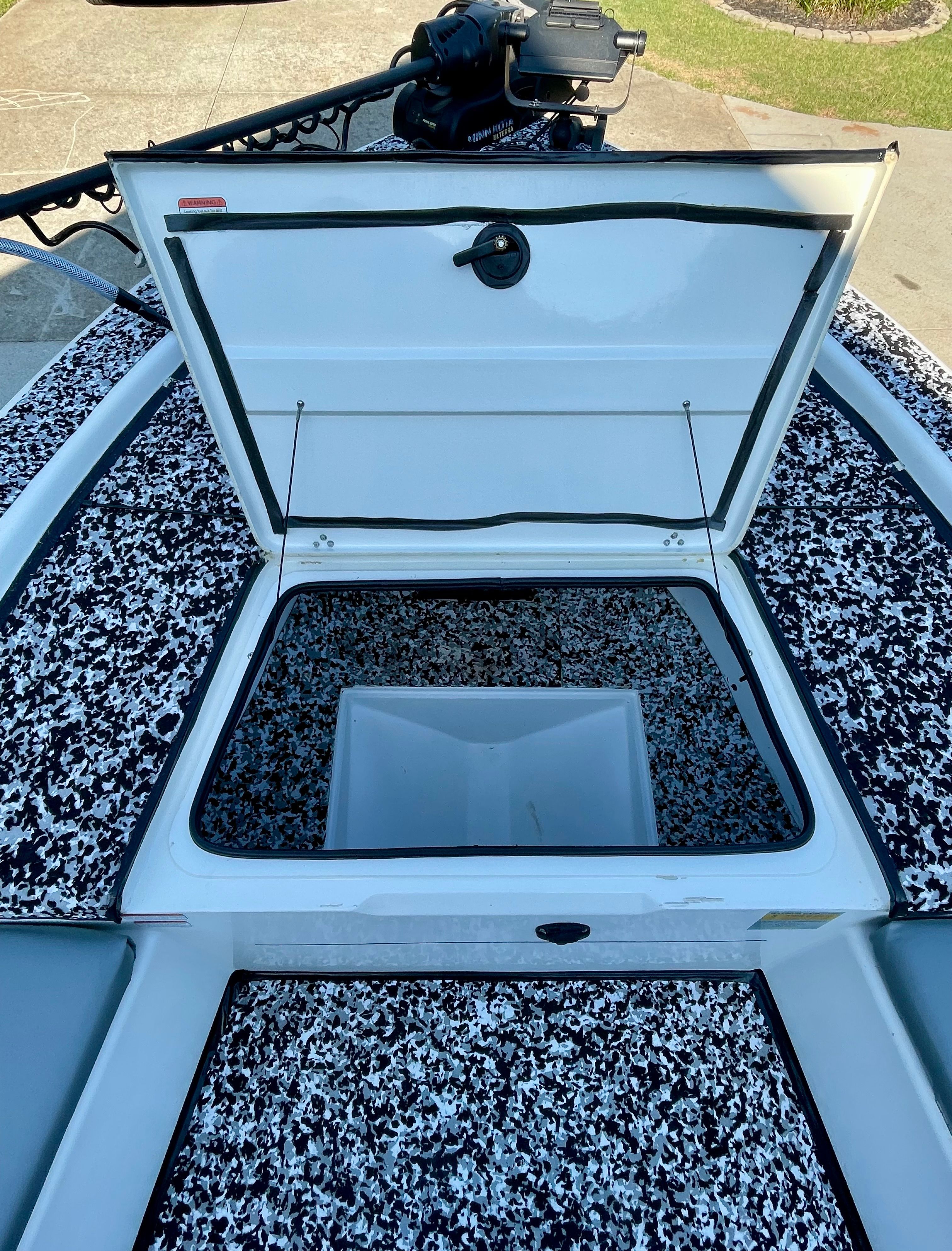 An open storage hatch on a boat with patterned deck flooring.