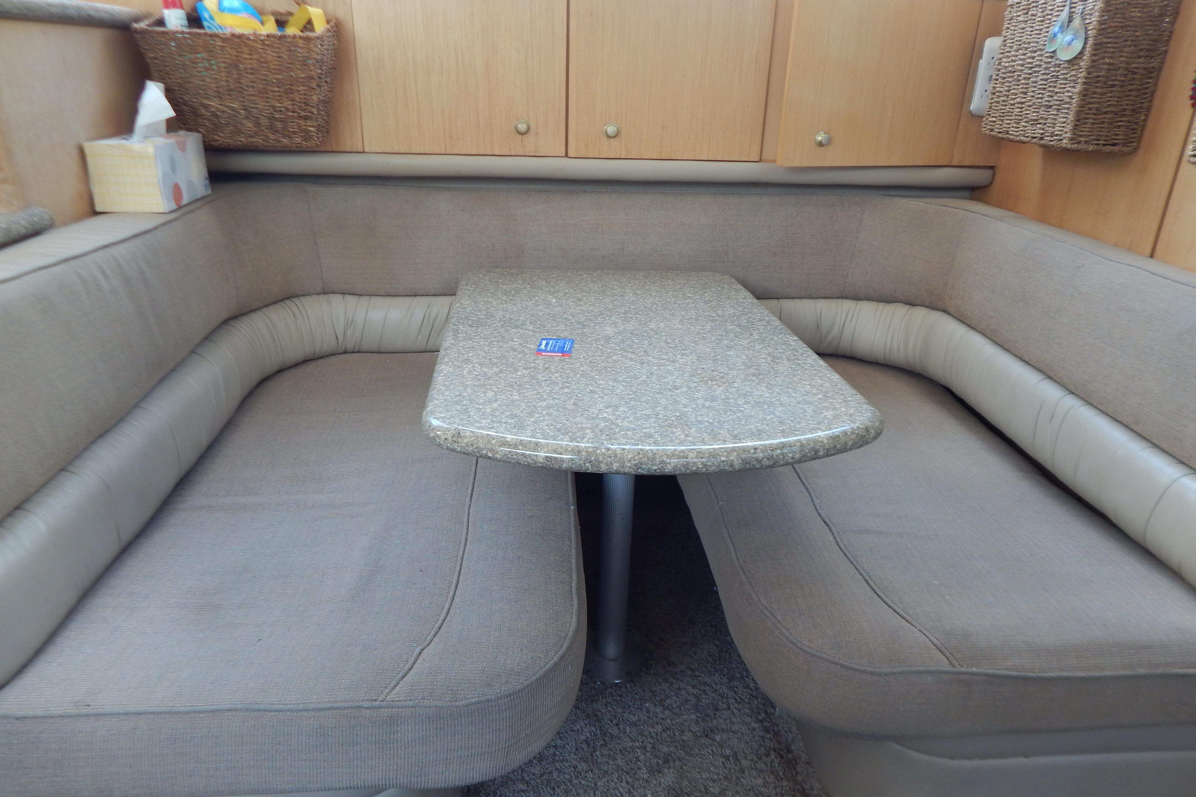 Cozy dining area in a 1998 Magnum 4100 SCR yacht with cushioned seating and a sleek table.