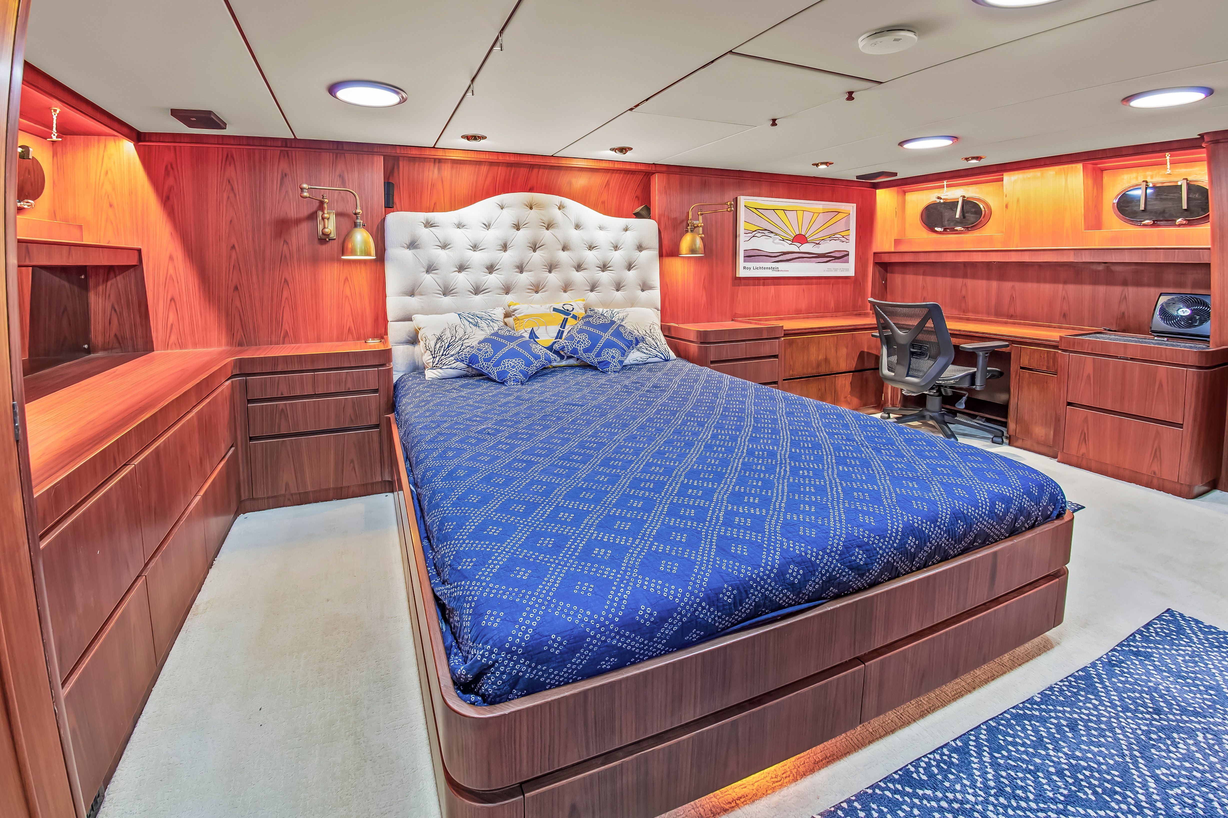 Luxurious bedroom with wooden furnishings and a large bed on a yacht.