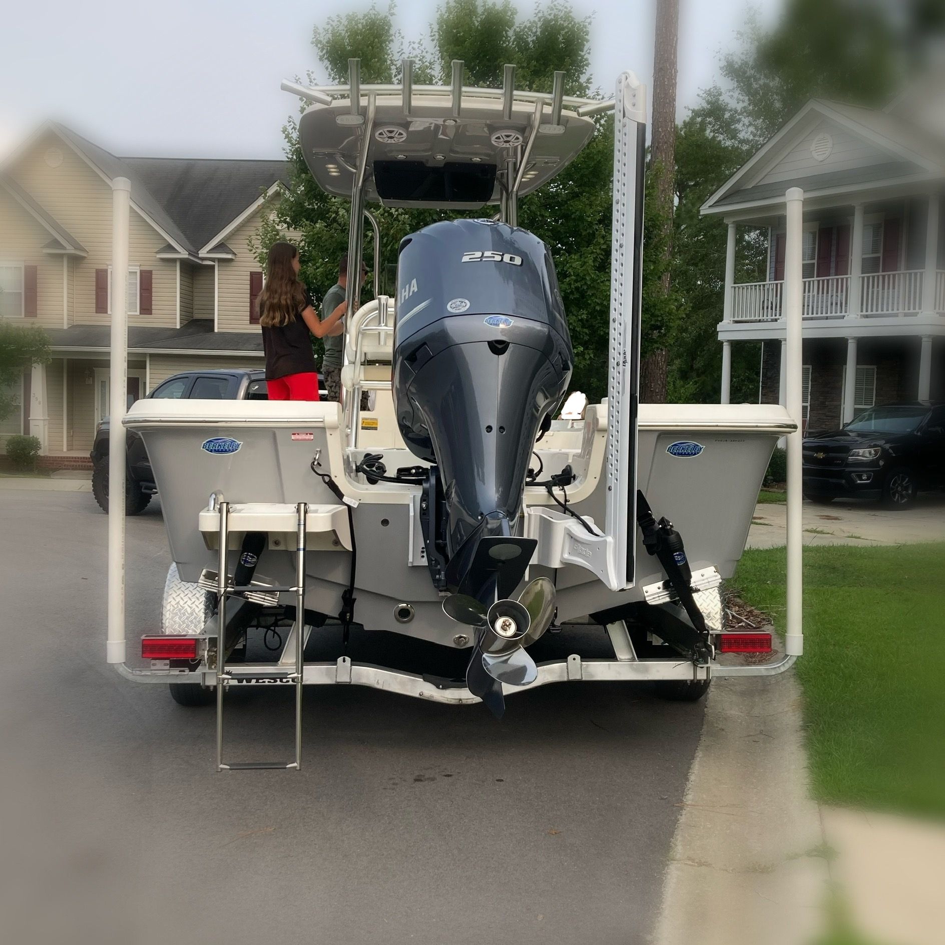 A 2023 Bulls Bay 2400 boat with a large outboard motor, parked in a residential area.