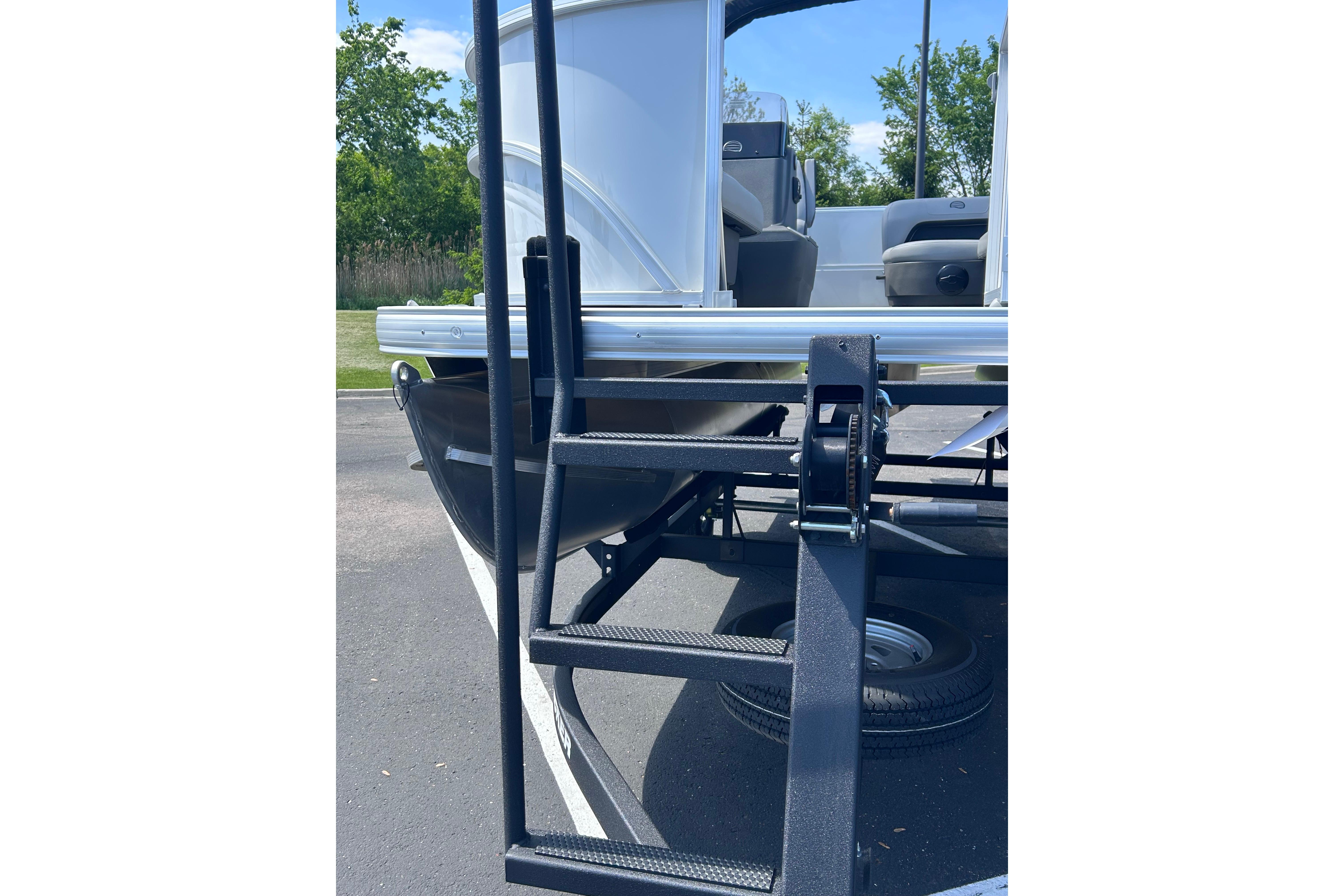2026 Sun Tracker Party Barge 16 DLX with trailer ladder and seating view.