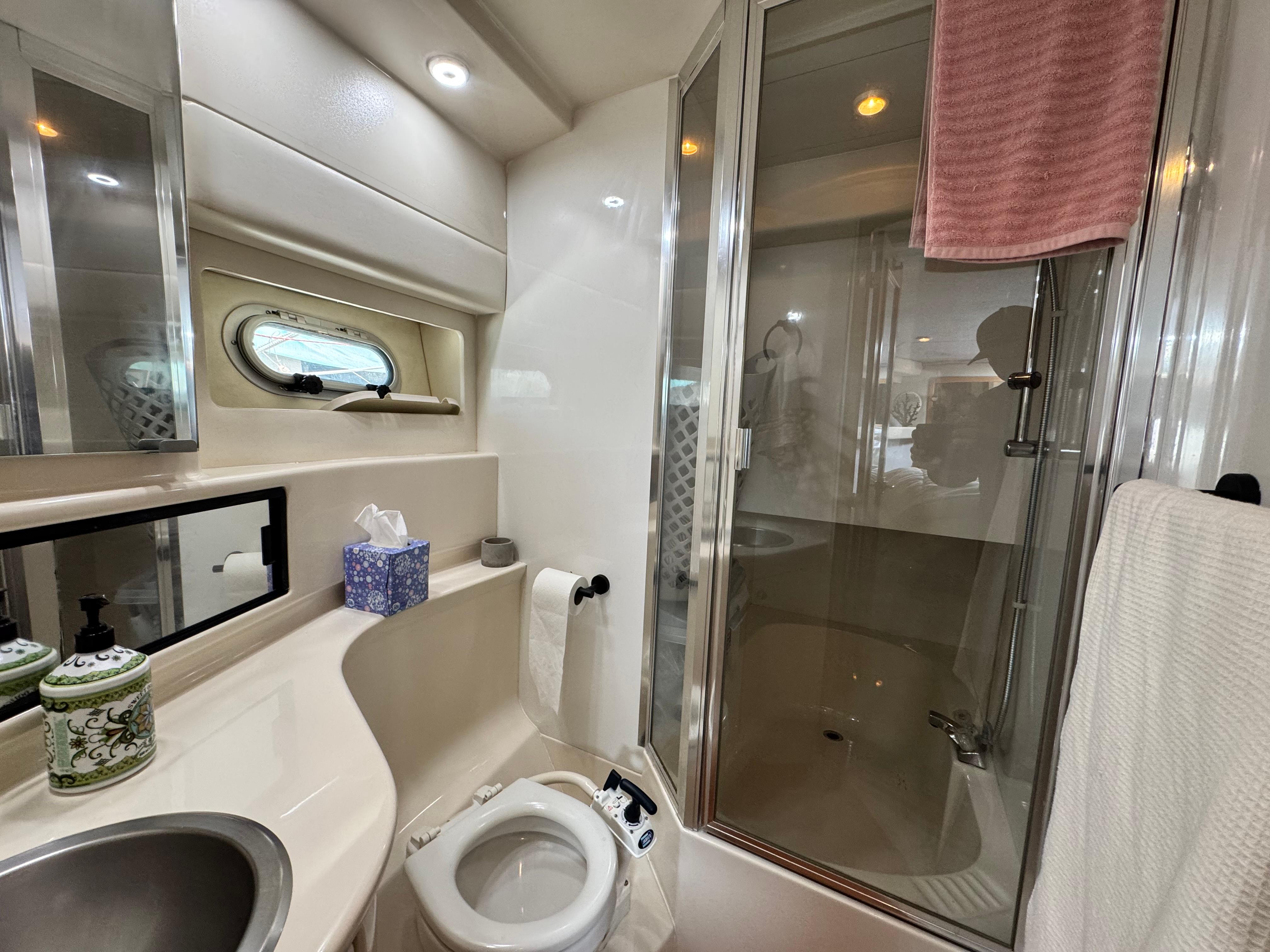 Bayliner 3988 2000 yacht bathroom with shower, sink, and porthole window.