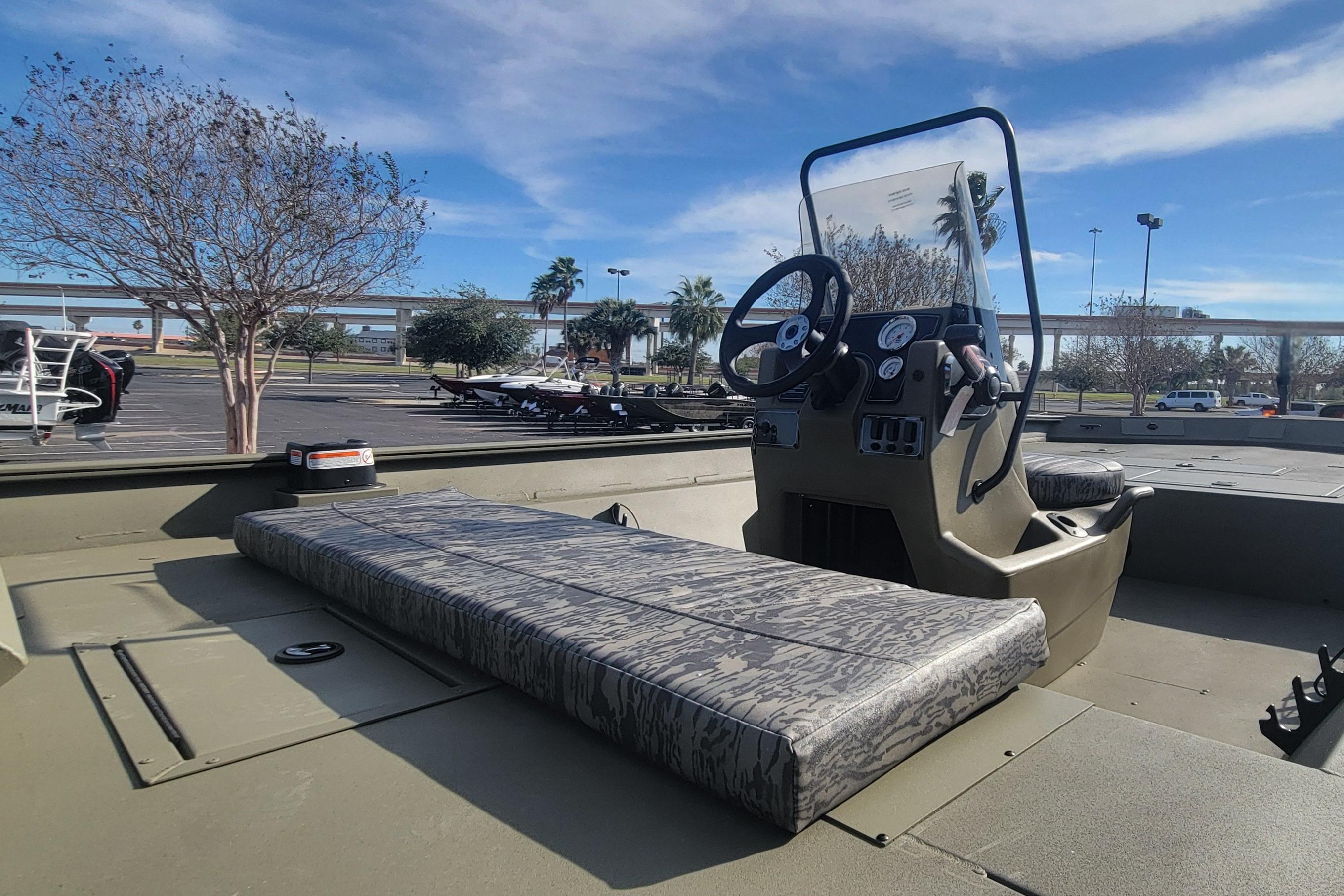 2026 Tracker Grizzly 2072 CC boat interior with console and seating, parked outdoors.