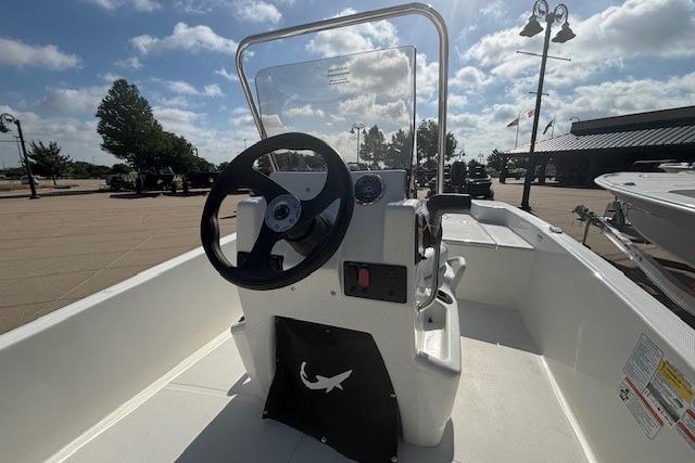 2026 Mako Pro Skiff 15 CC boat console with steering wheel, outdoors under a partly cloudy sky.