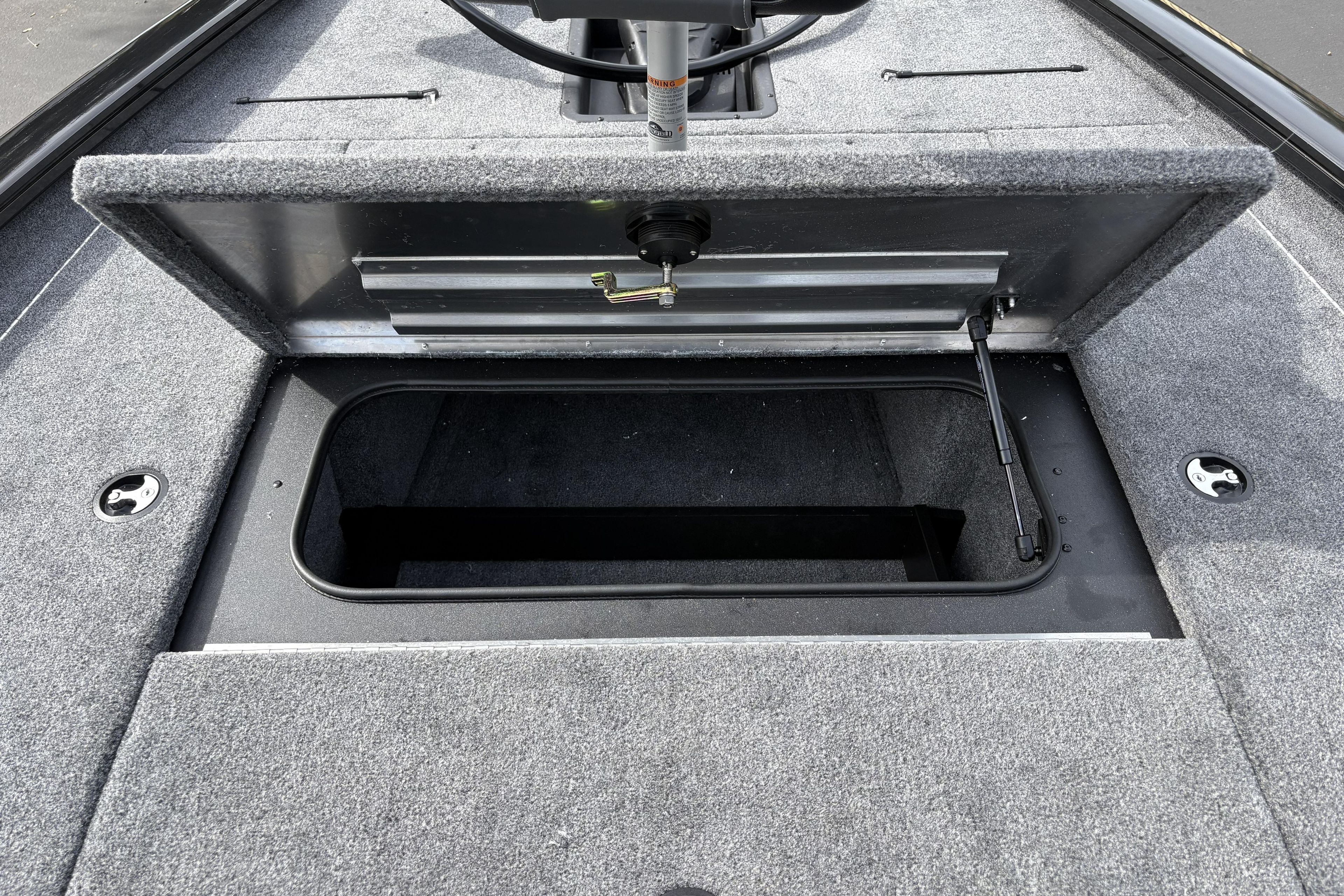 Open storage compartment on 2026 Tracker Pro Team 195 boat, featuring carpeted interior.