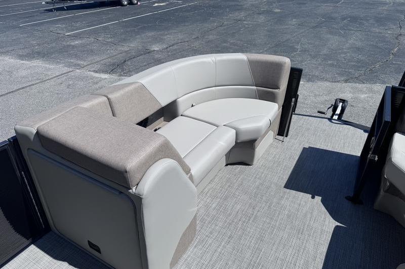 2027 Manitou Aurora 23 RF SHP boat interior with curved seating in a parking lot.