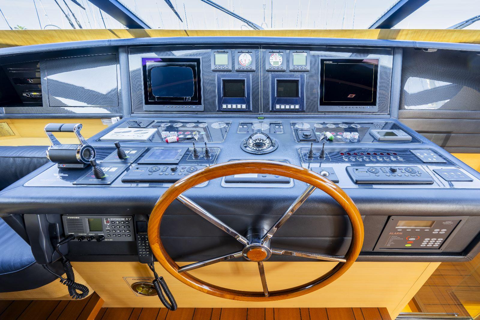 Helm of 2011 Maiora 27 yacht with wooden steering wheel and navigation controls.