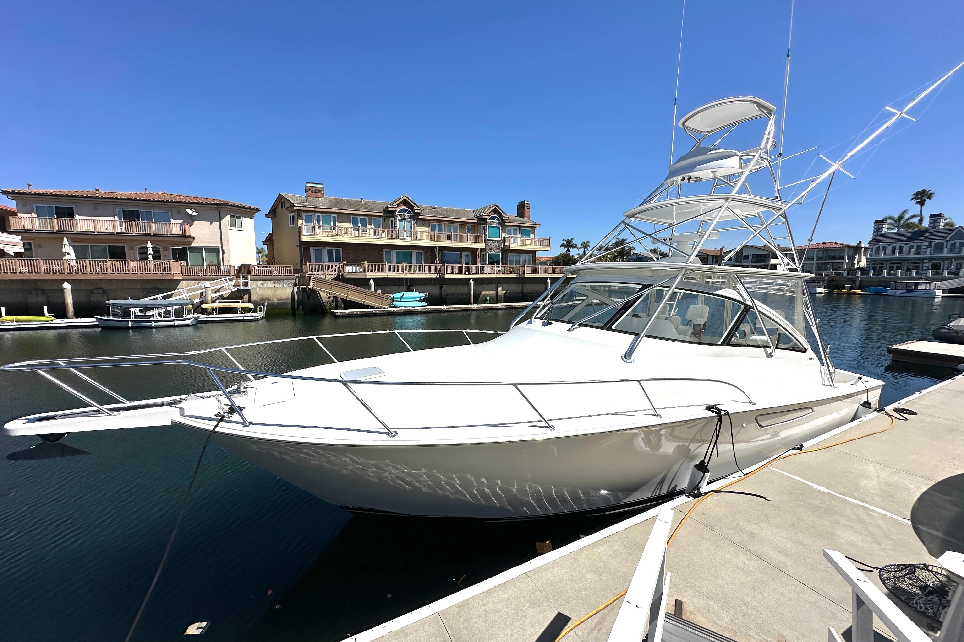 2012 Viking 42 Open yacht docked in a sunny marina, surrounded by waterfront homes.