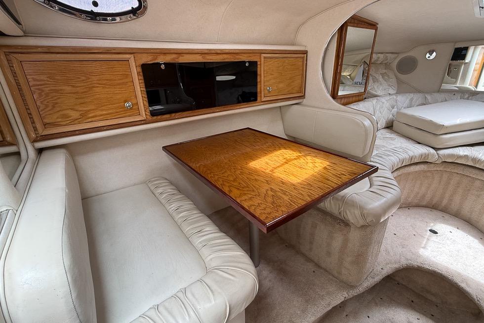 Interior of 1999 Sea Ray 290 Sundancer with wood table and cushioned seating.