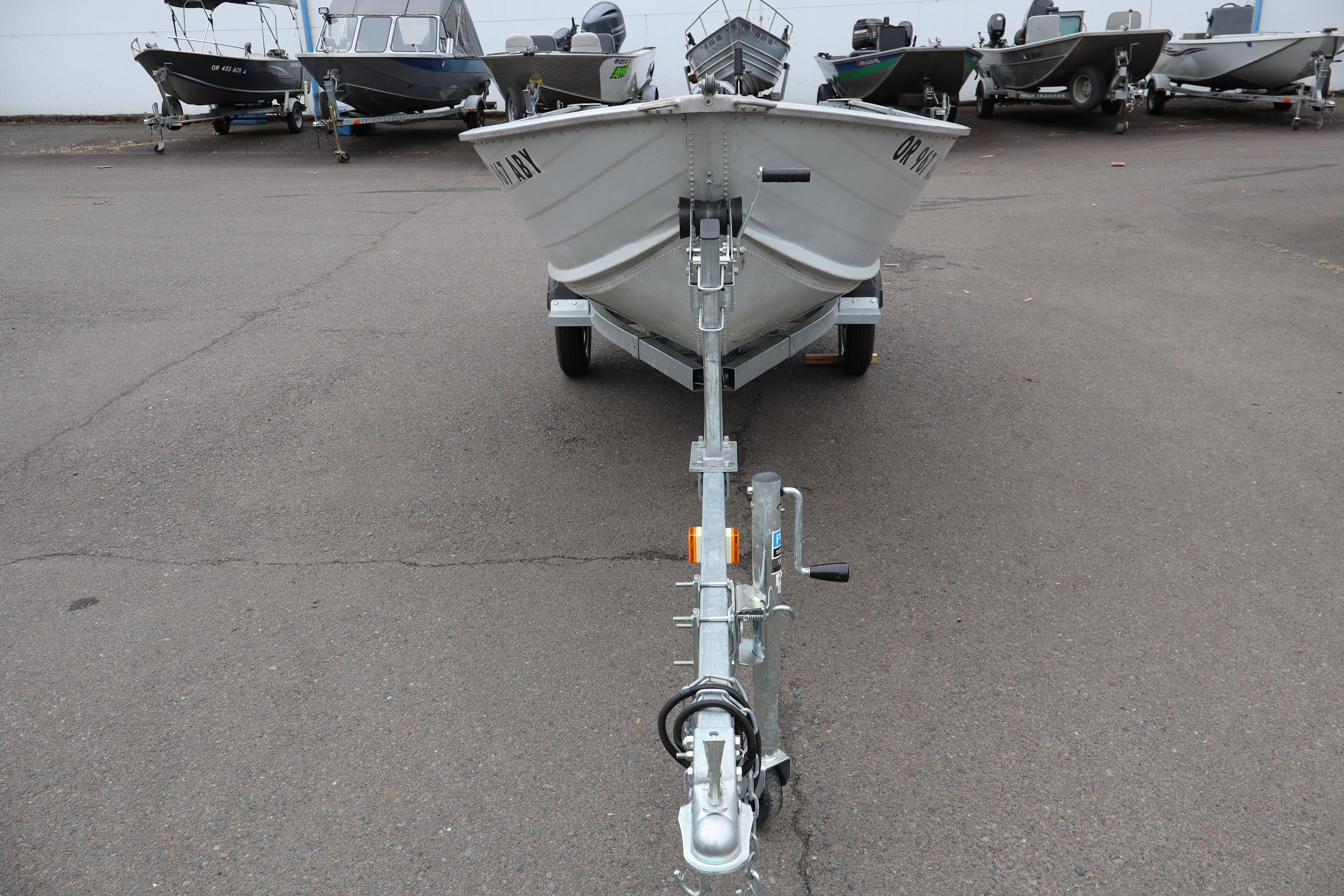 2003 Smoker Craft Alaskan 13 boat on trailer, parked in a lot with other boats.