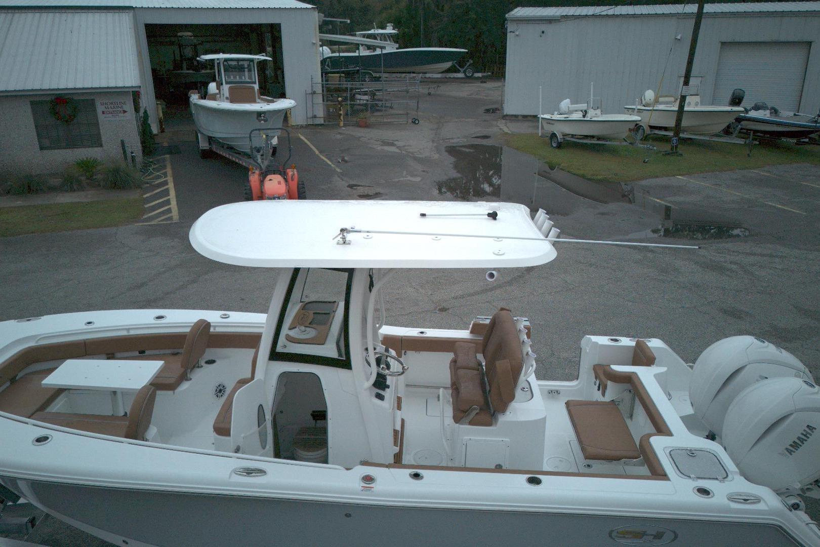 2026 Sea Hunt Gamefish 25 boat with dual engines, docked near storage buildings.
