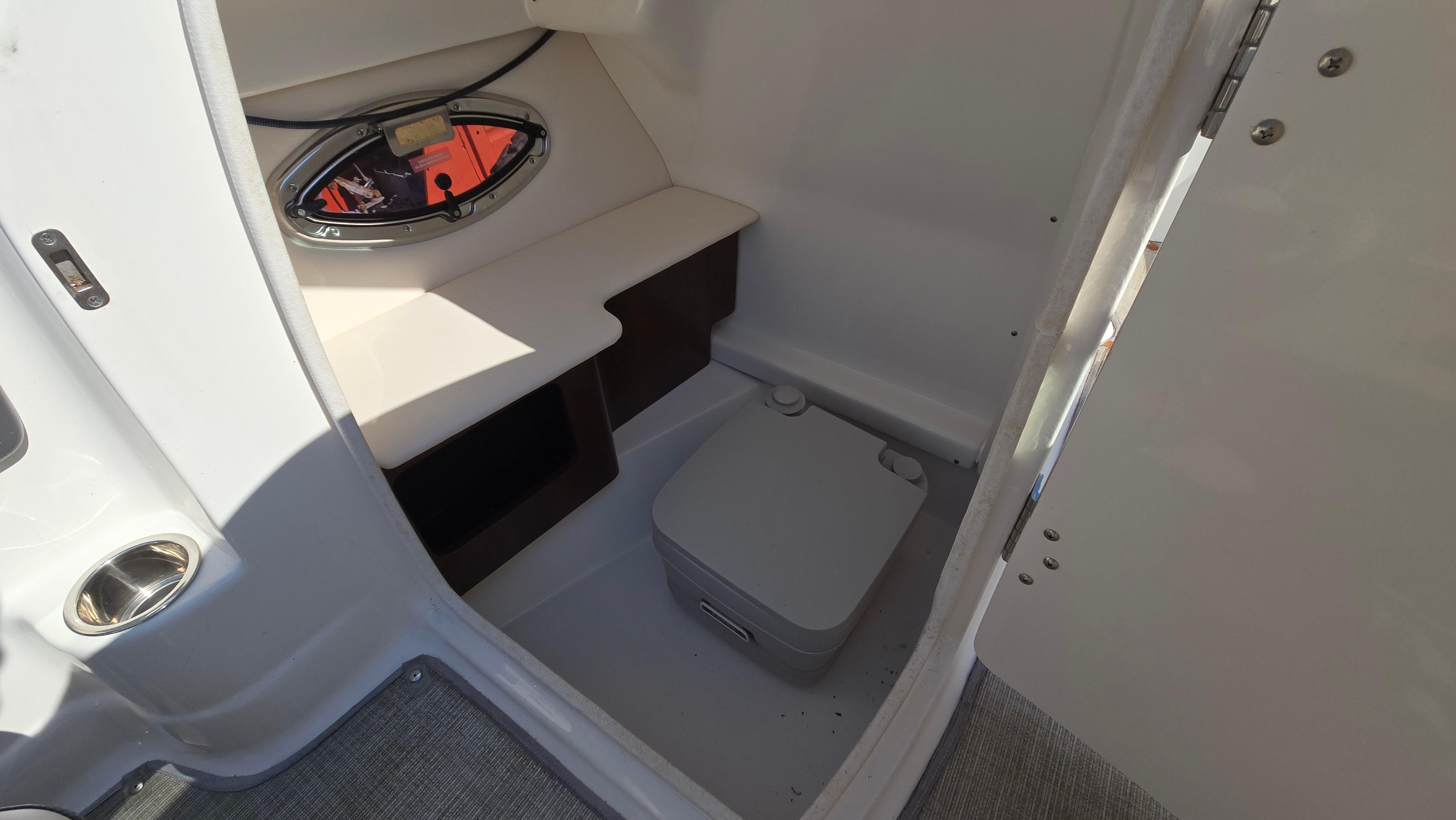 2018 Chaparral 224 Sunesta boat interior with compact toilet and window.