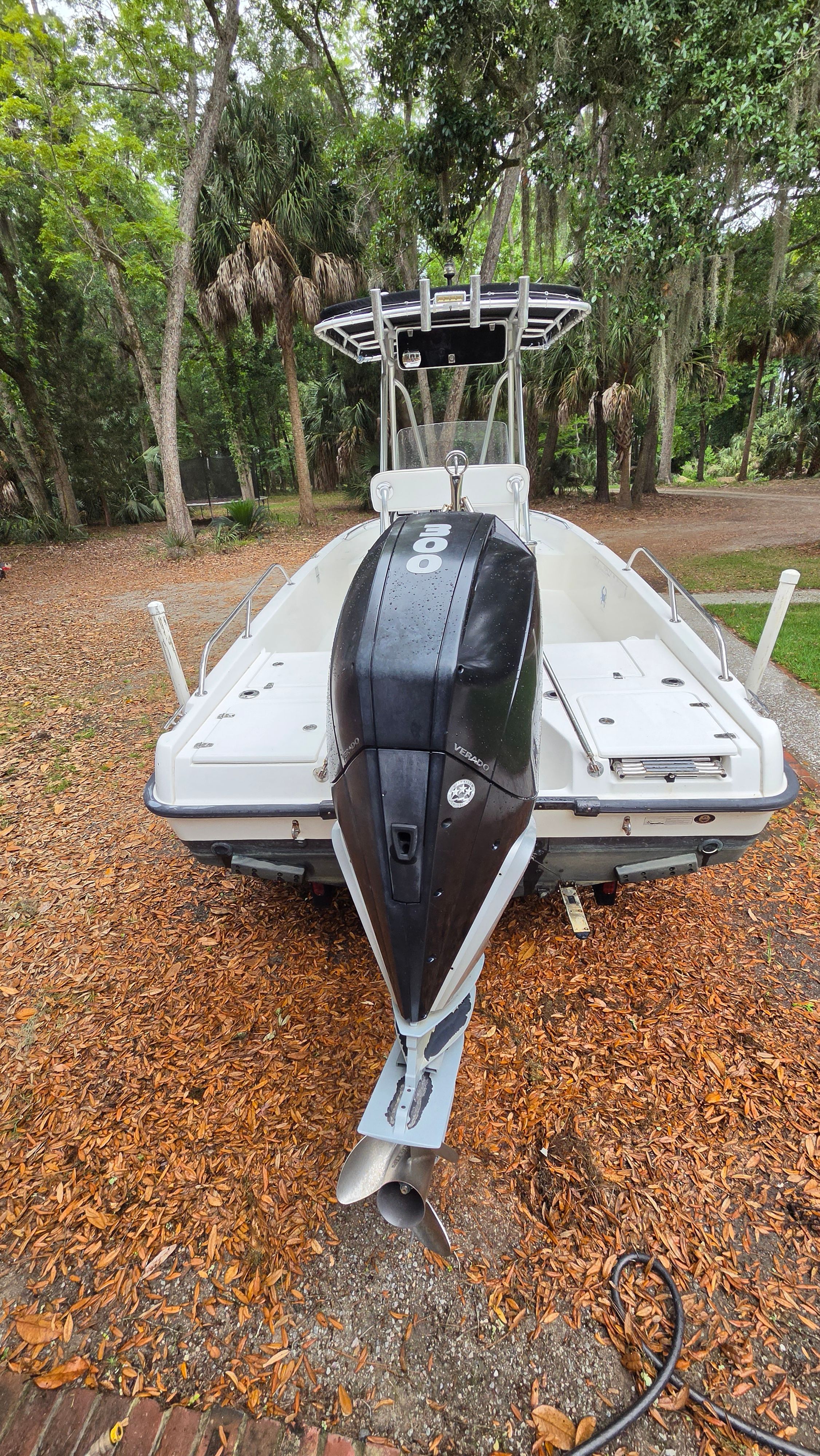 A 2008 Boston Whaler 230 Dauntless with an outboard motor, surrounded by trees.