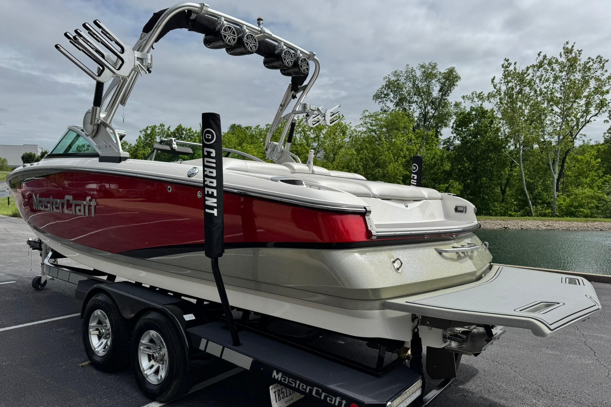 2014 MasterCraft X-35 boat with red and white design on a trailer by a lake.