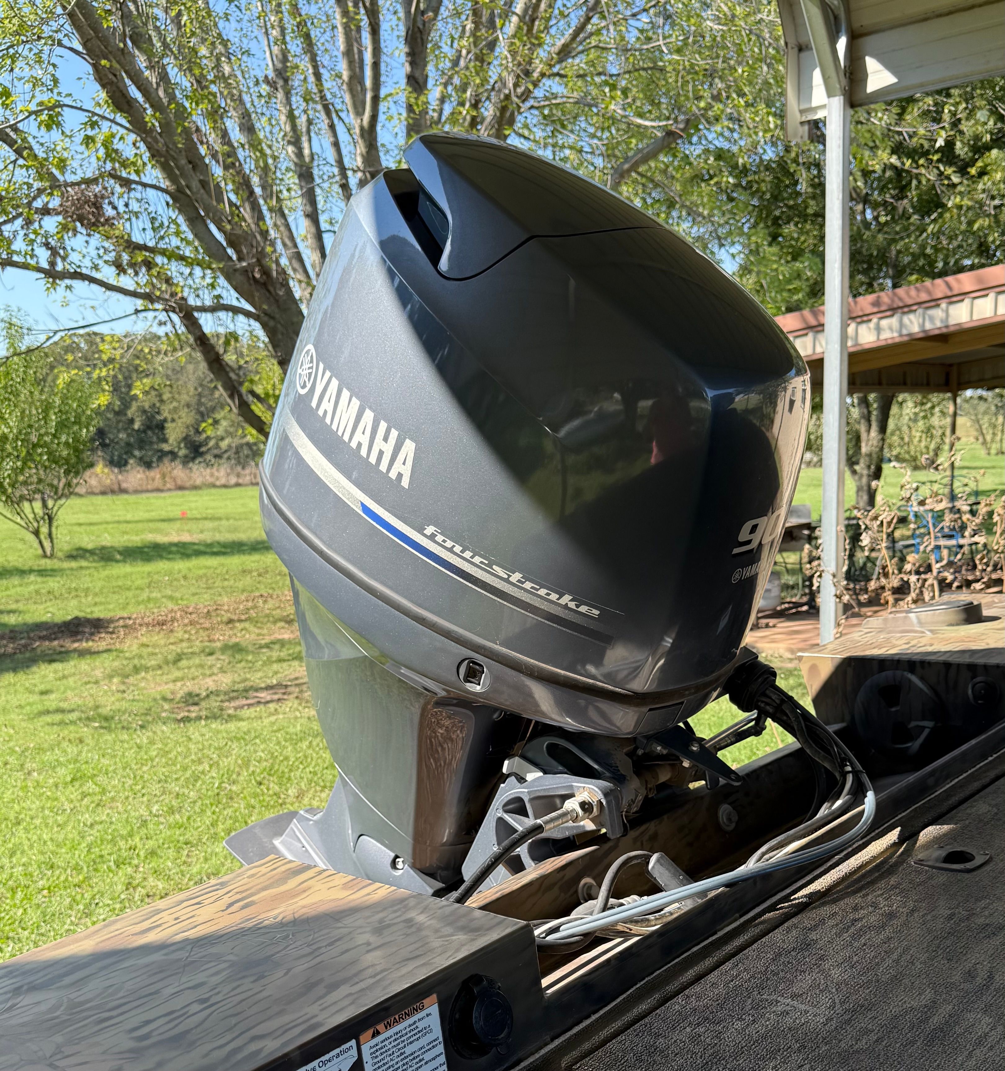 A Yamaha outboard motor is mounted on a boat situated in a green, wooded area.