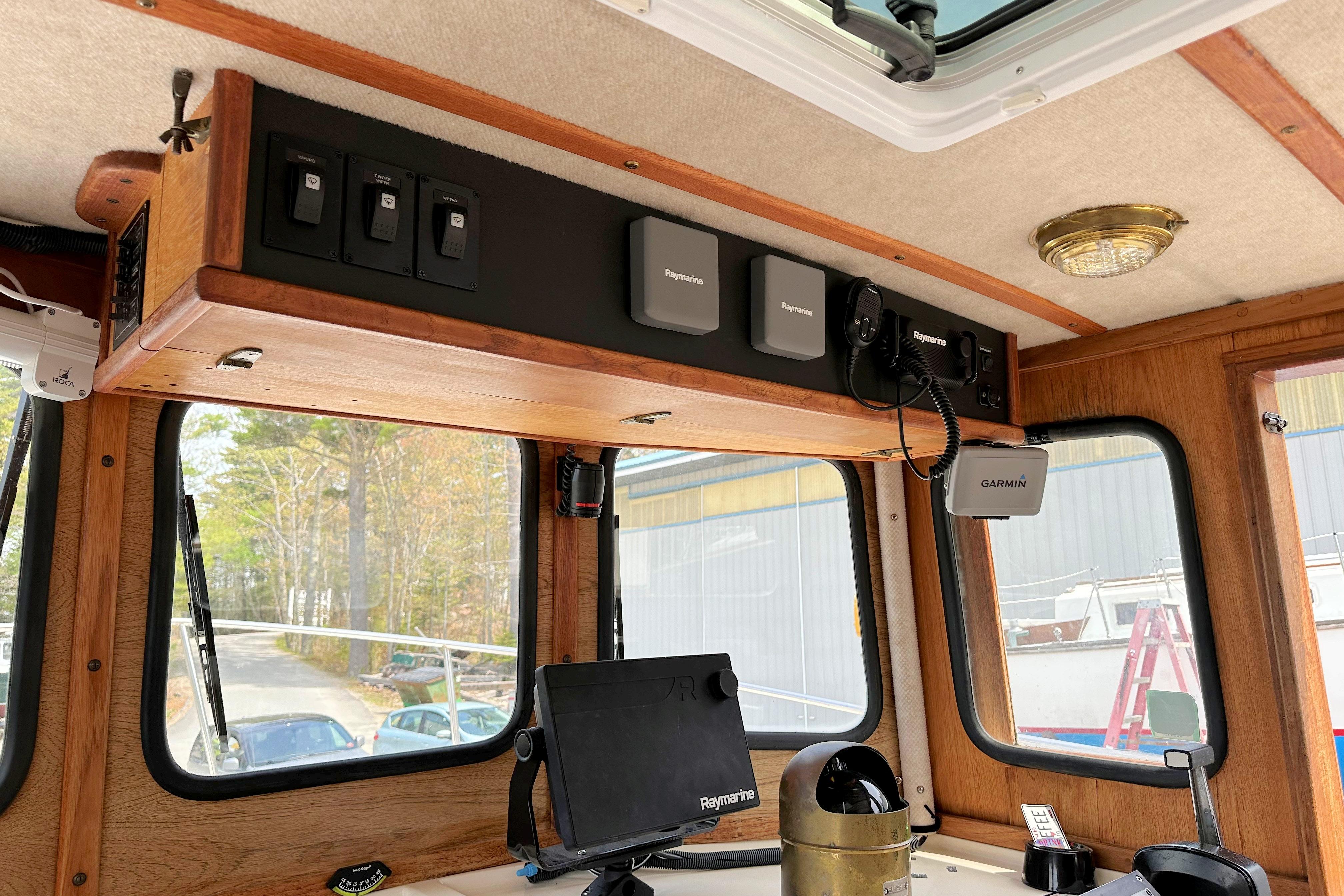 Interior of a 1985 Nordic Tug 26 with navigation equipment and wooden paneling.