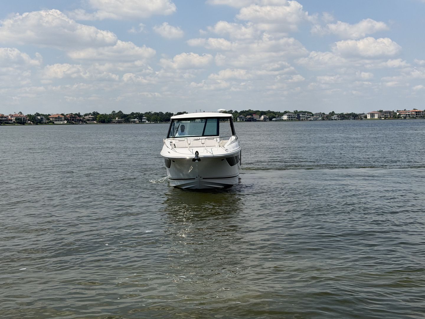Sea Ray Sundancer 320 Outboard 2026 on calm water under cloudy sky.