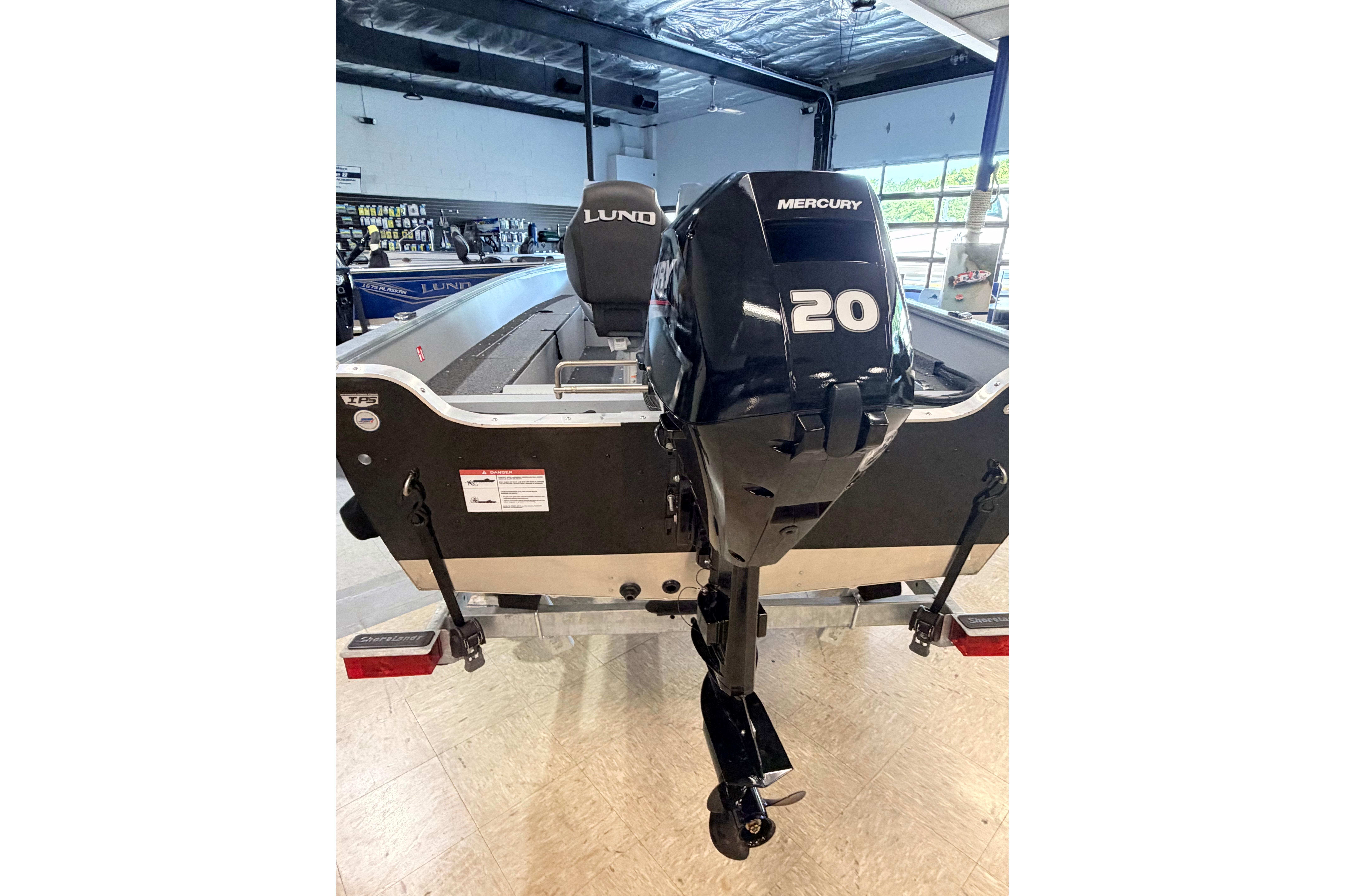 2027 Lund 1600 Fury SS boat with Mercury 20 HP outboard motor in showroom.