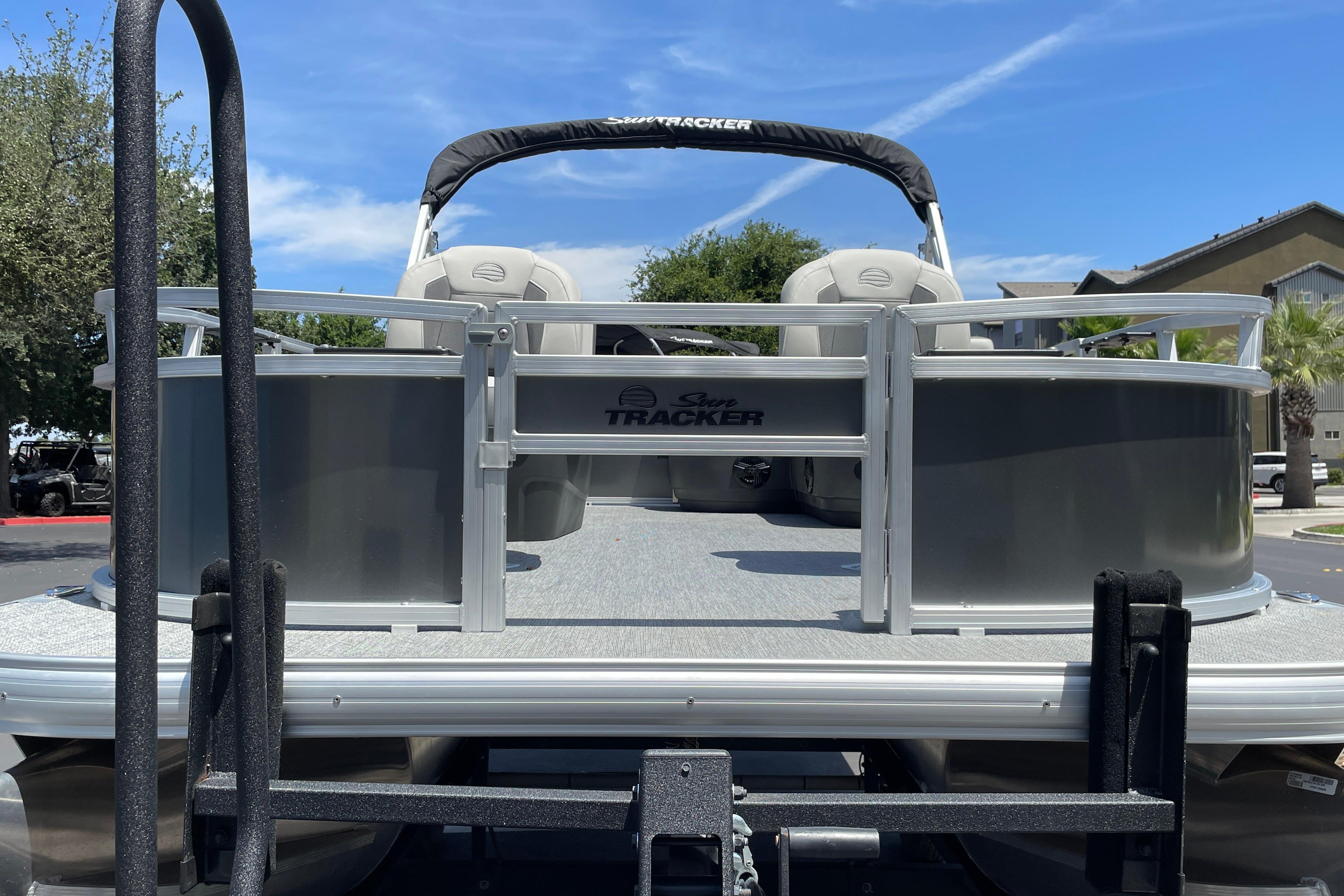 2026 Sun Tracker Bass Buggy 16 XL Select pontoon boat on trailer, sunny day.