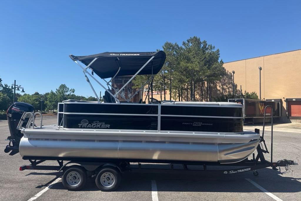 2026 Sun Tracker Party Barge 20 DLX pontoon boat on trailer in parking lot.