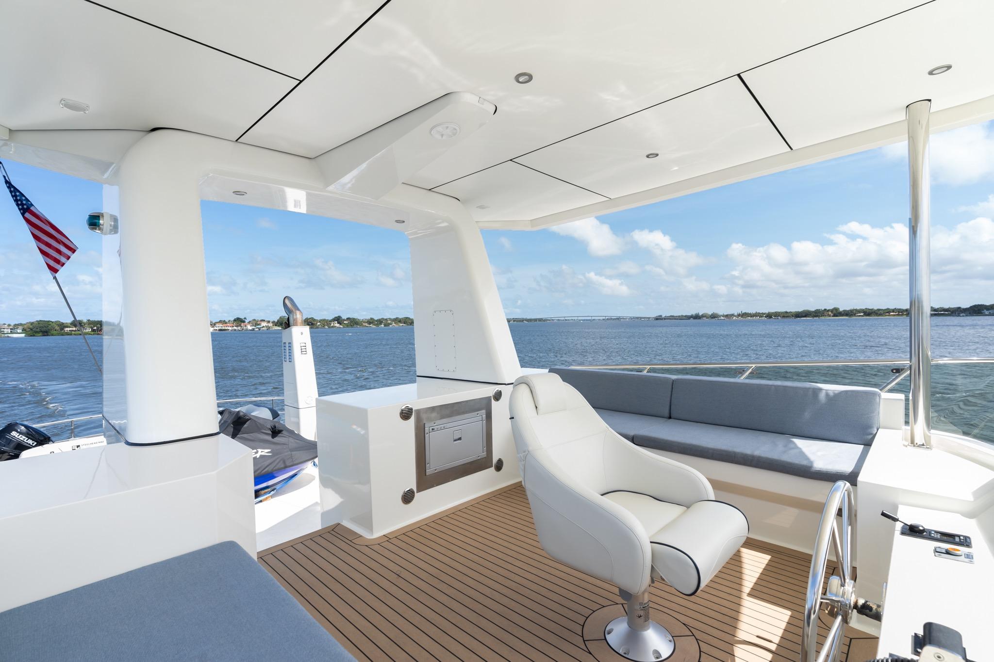 Luxurious 2022 Alm Trawler Delfino 64 yacht deck with seating, overlooking serene waters.