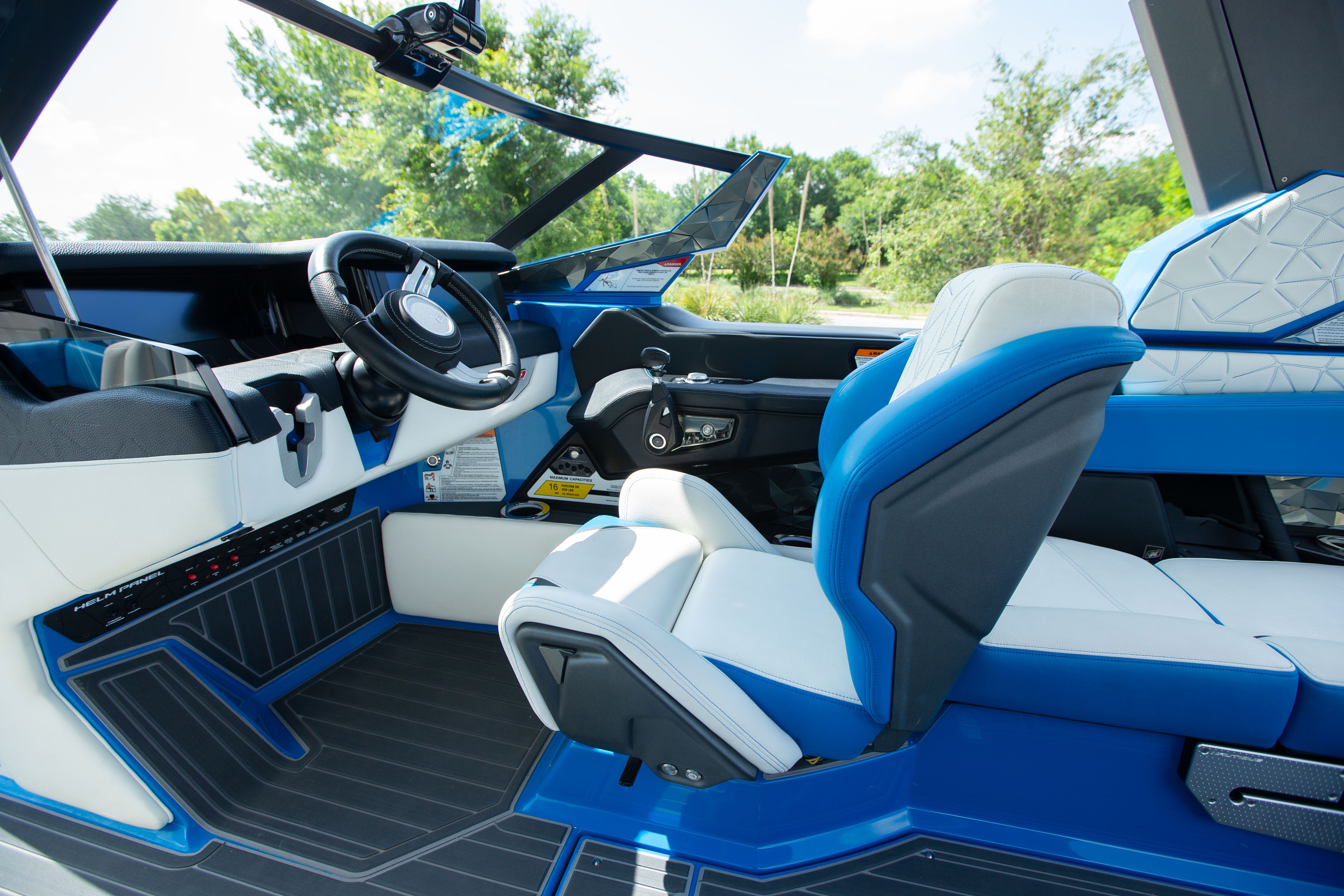 Interior of a modern boat with blue and white seats and steering wheel.