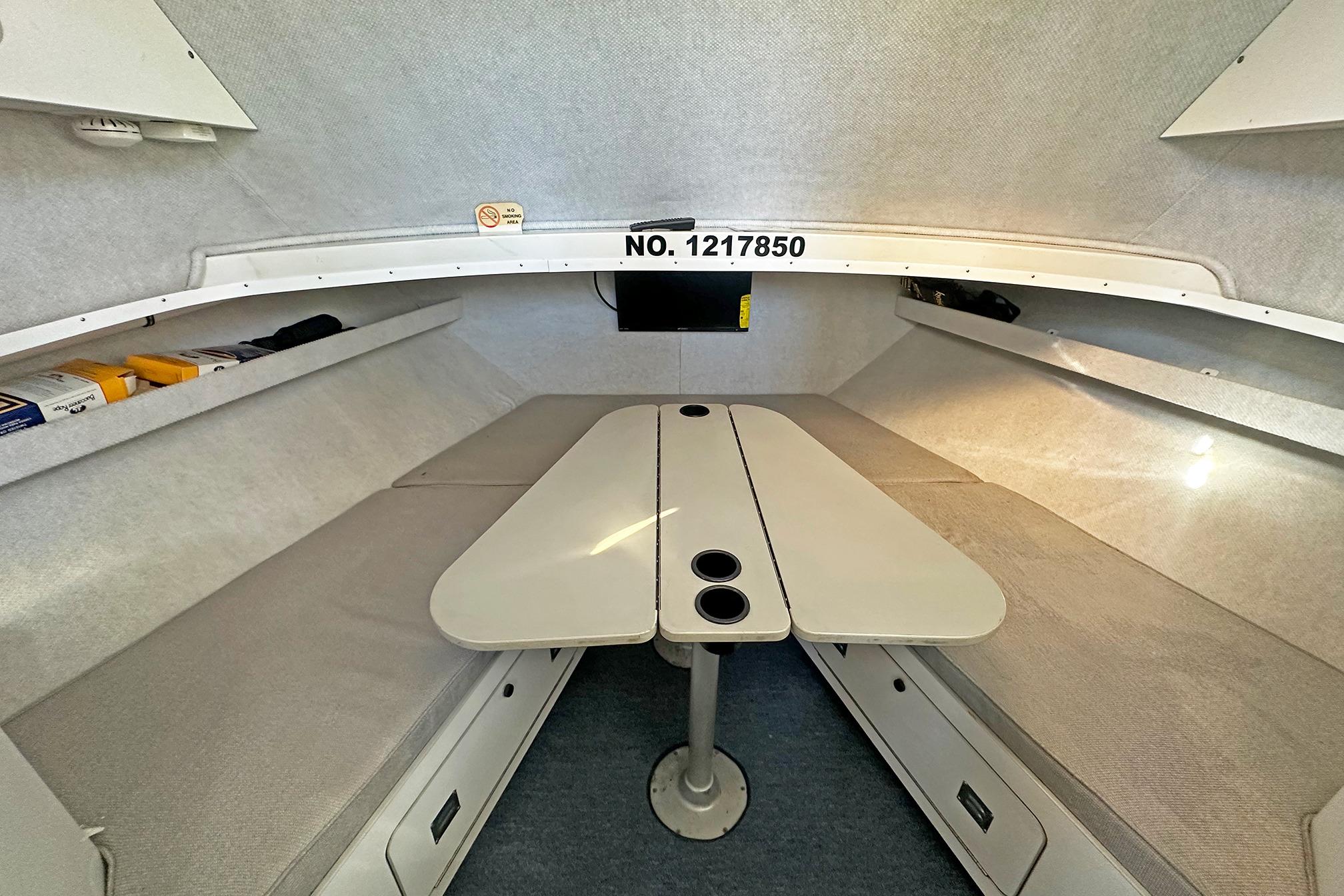 Interior cabin of a 1990 Boston Whaler 36 Defiance boat, featuring seating and storage.