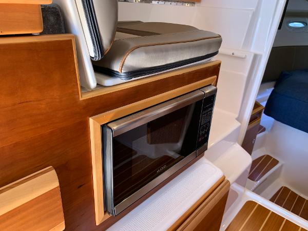 2021 Cutwater C-32 CB interior with built-in microwave and wooden cabinetry.