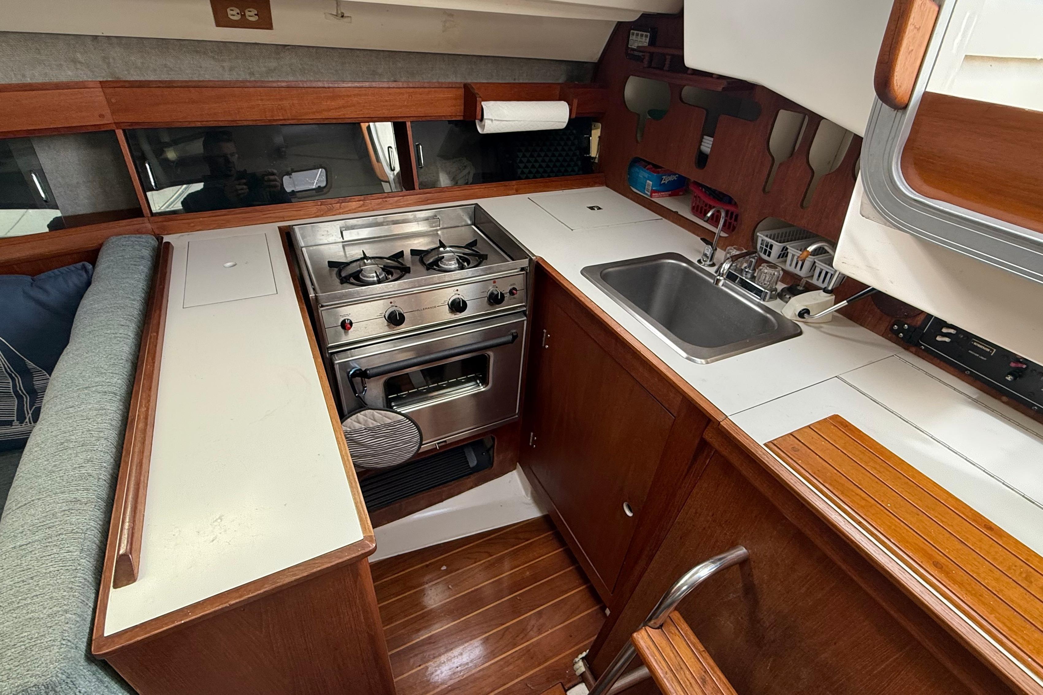 1984 Hunter 31 yacht kitchen with stove, sink, and wooden cabinetry.
