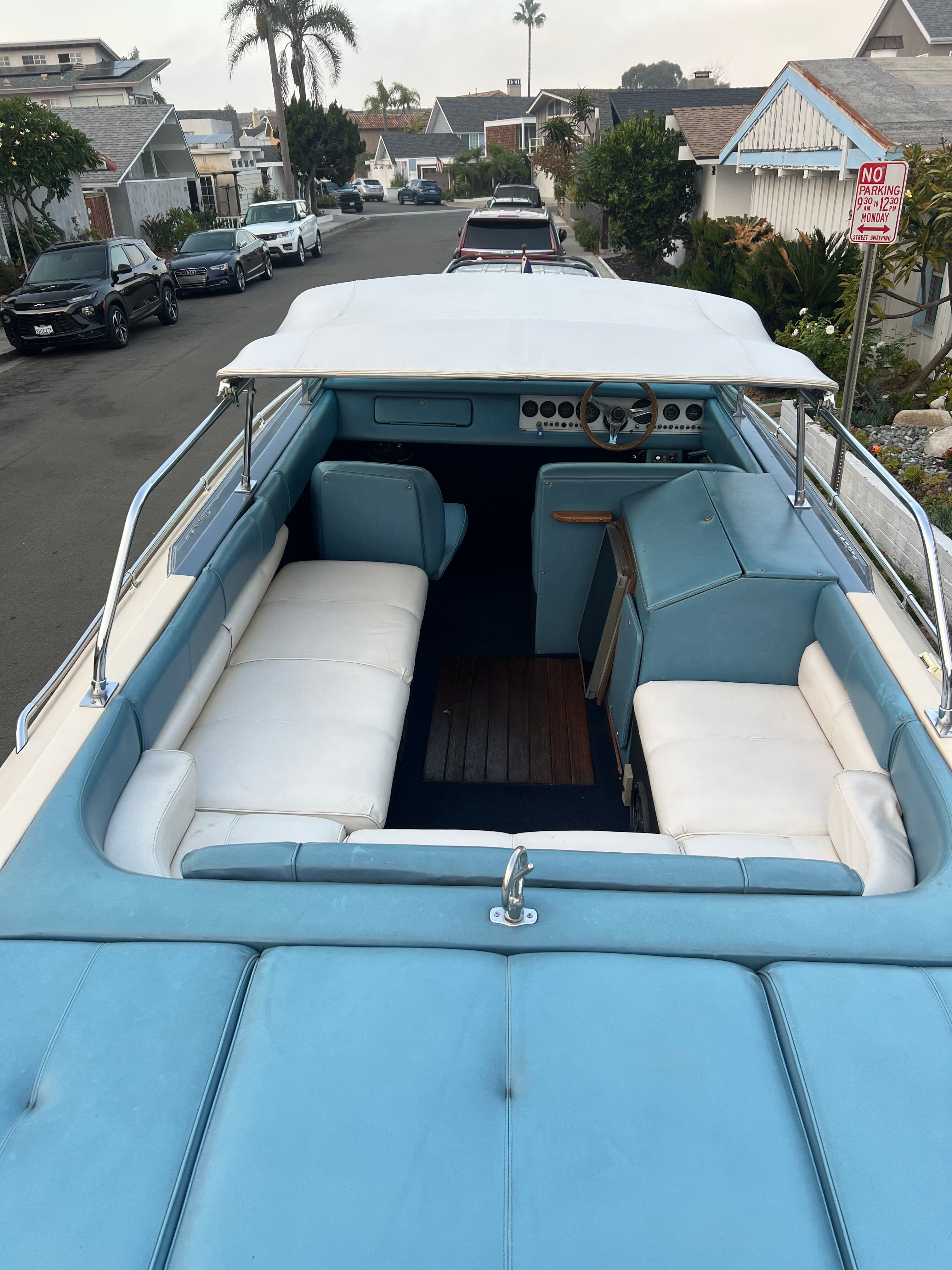 1985 Century Coronado Cardel boat with blue and white interior, parked on a residential street.