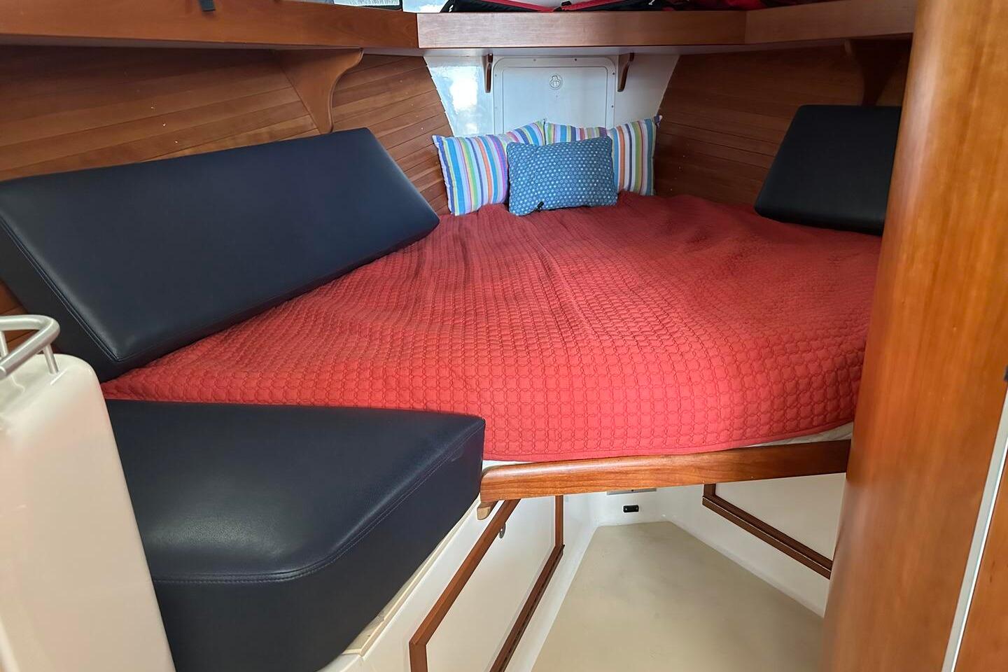 Cozy cabin interior of 2002 True North 38 boat with red bedding and cushions.
