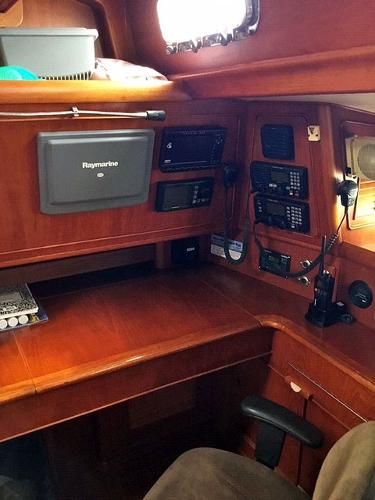 Interior view of a sailboat with wooden desk and navigation equipment.