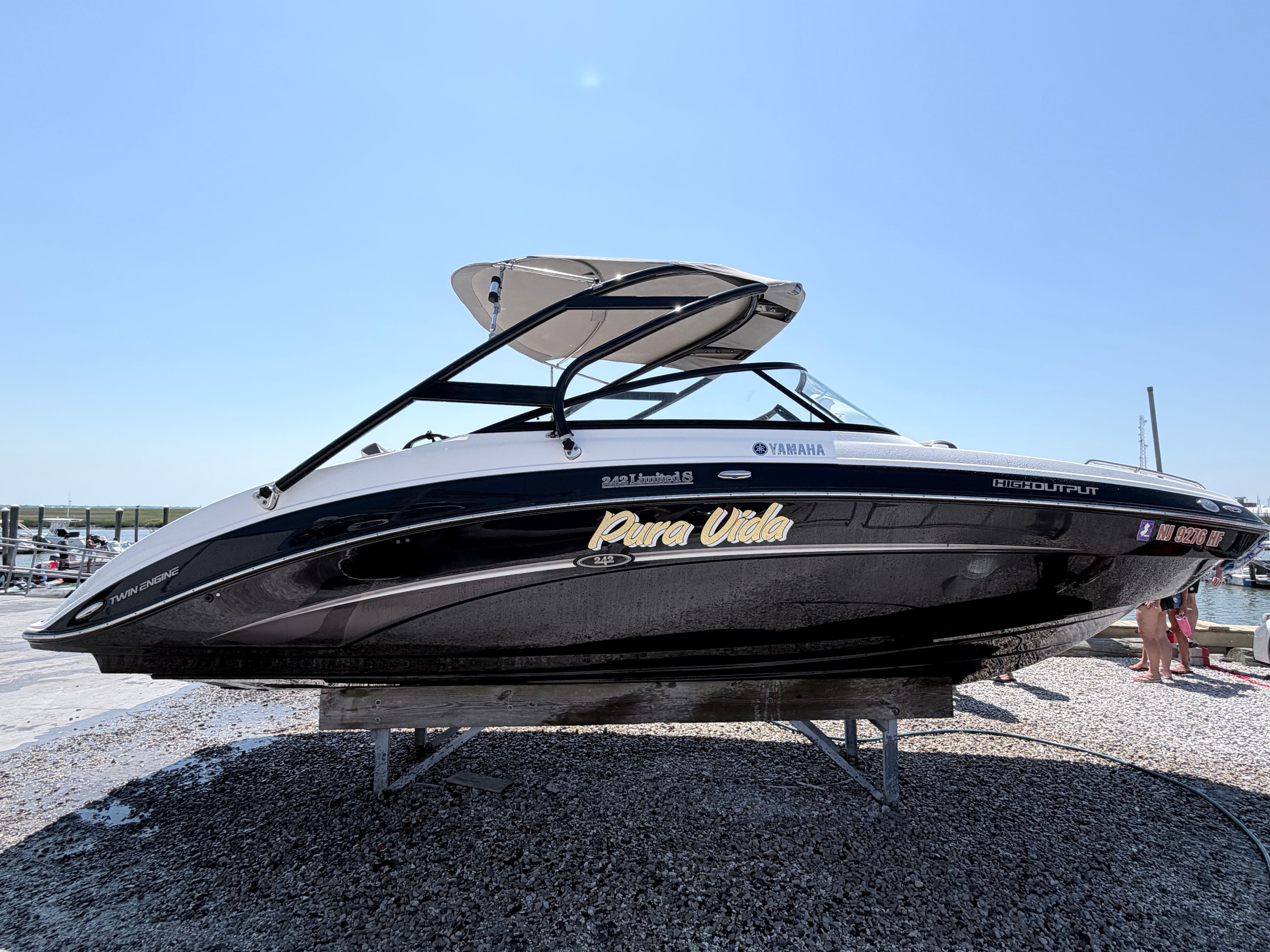 A 2014 Yamaha 242 Limited S boat is on a stand on land.