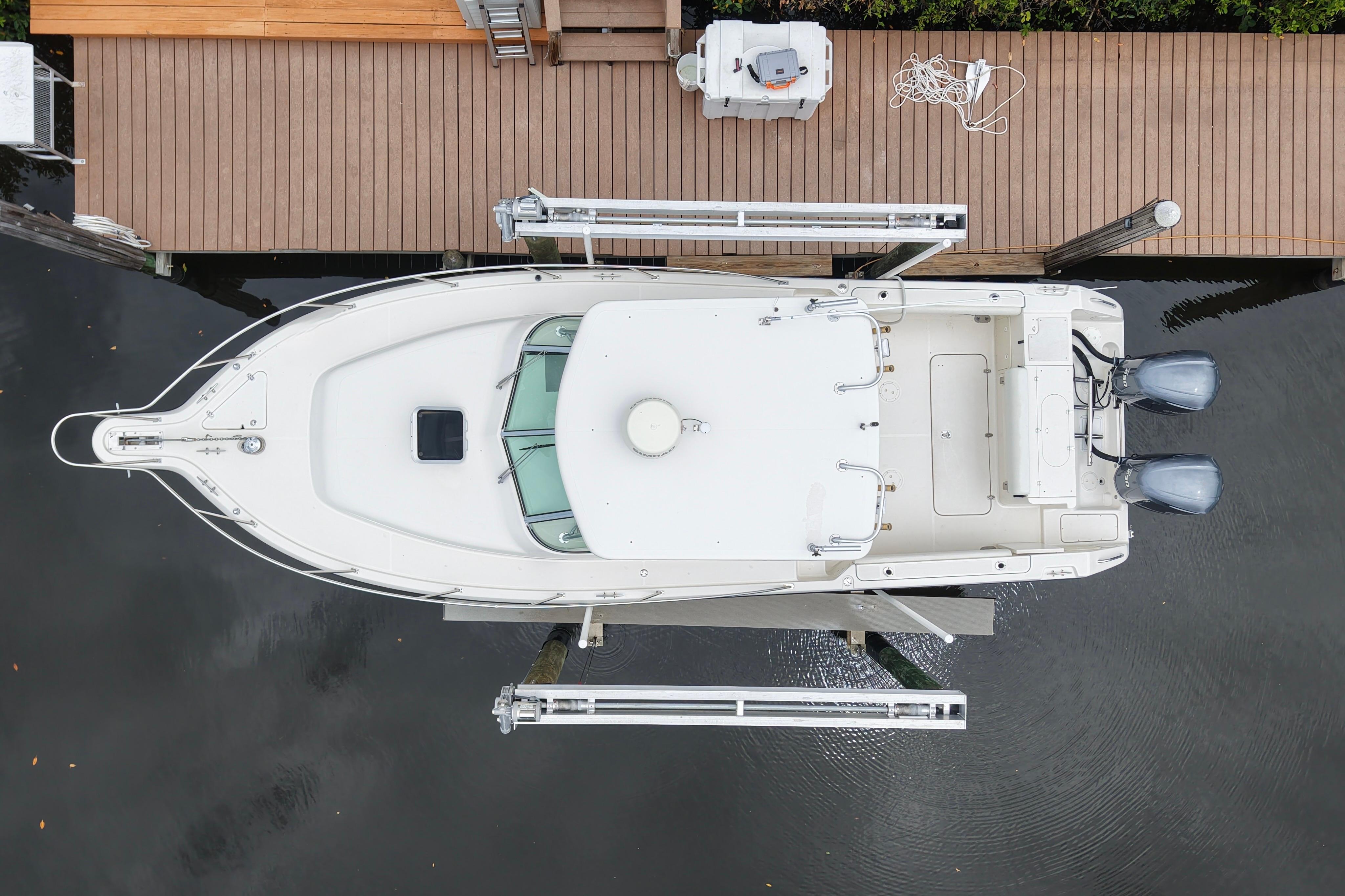 Overhead view of a 2005 Pursuit 3070 Offshore boat docked by a wooden pier.