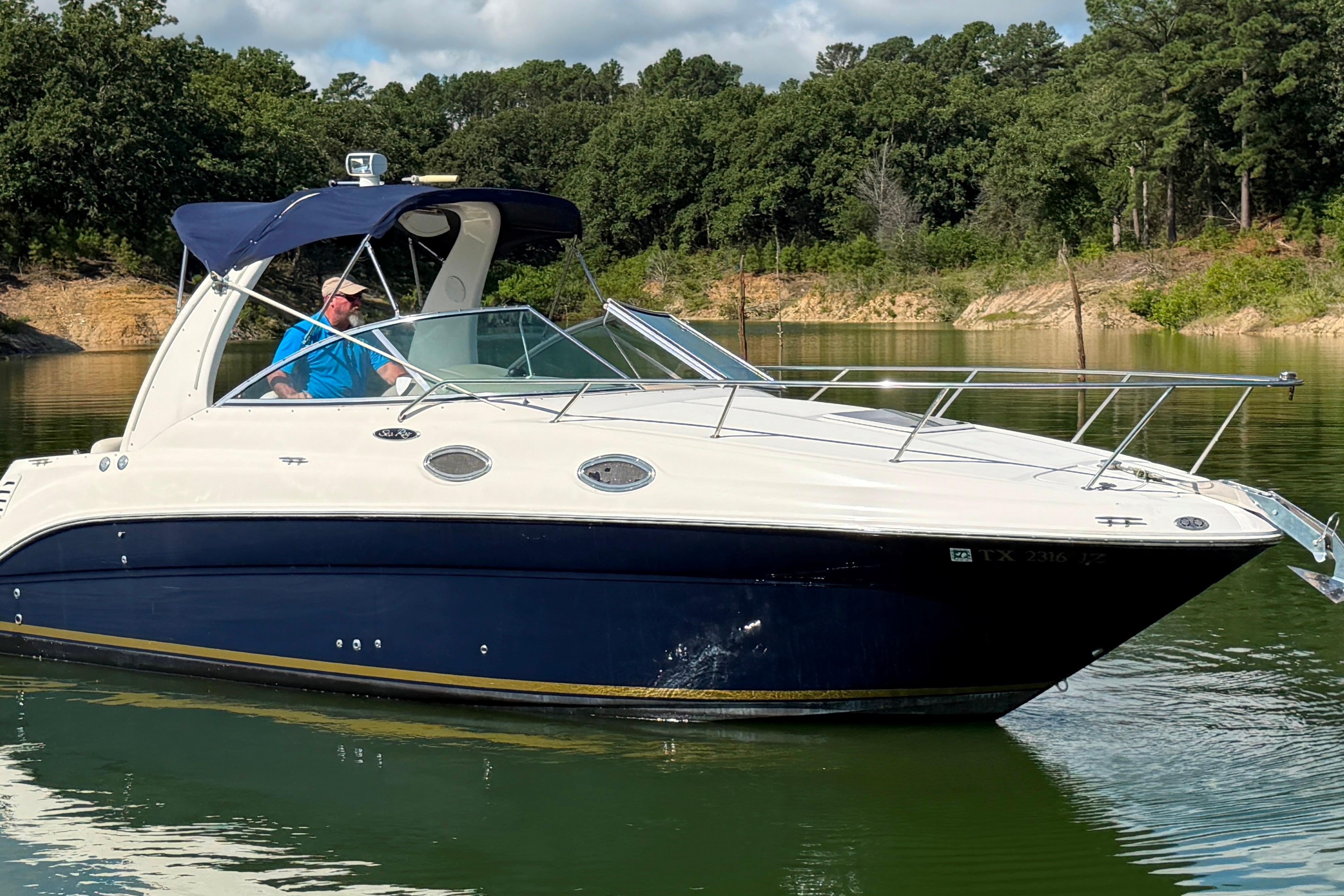 2004 Sea Ray Sundancer 260 cruising on a serene lake with lush forest backdrop.