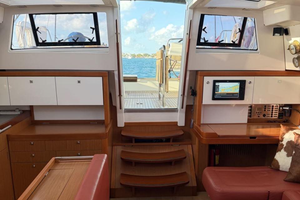Interior of 2015 Beneteau Sense 55 yacht, featuring navigation station and wooden cabinetry.
