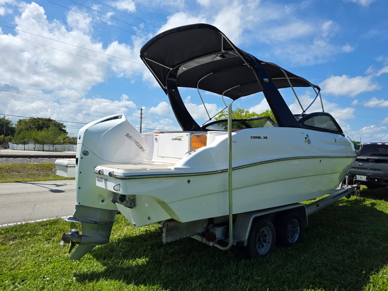 A 2025 Coral 26 boat on a trailer outdoors under a blue sky.