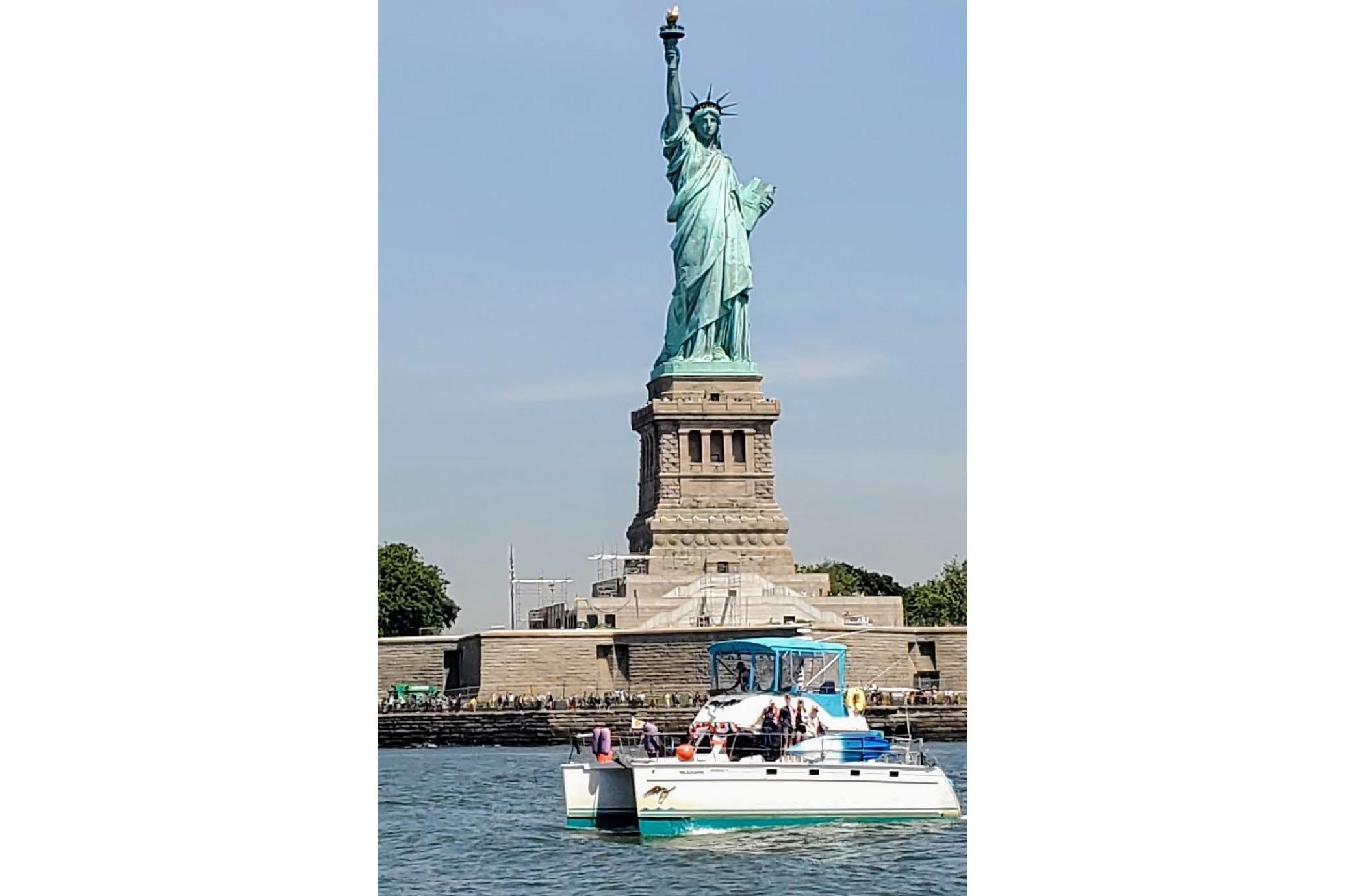 PDQ 34 Powercat boat near Statue of Liberty, 2004 model, sunny day.