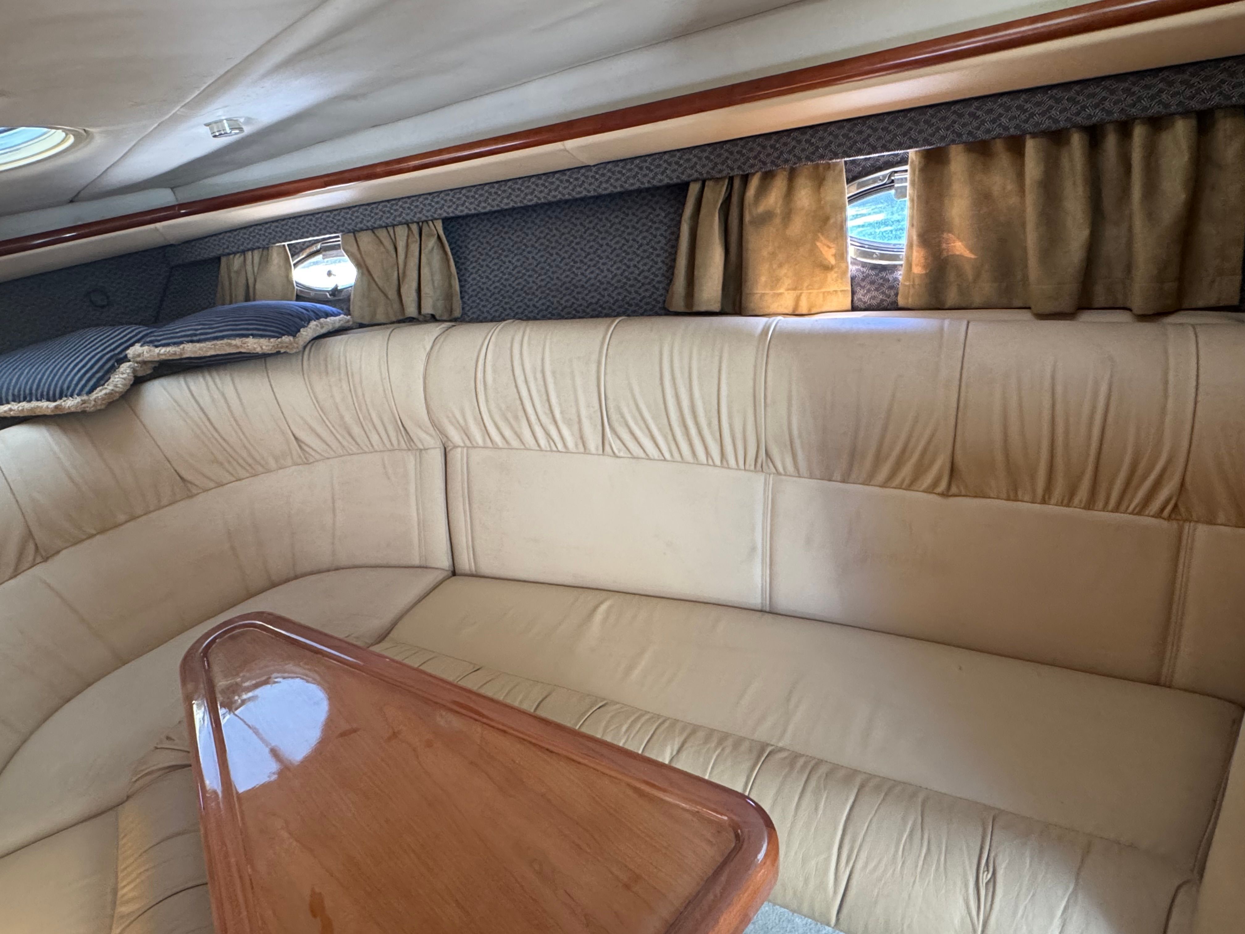 Interior of a 2003 Cobalt 360 with beige upholstered sofa and wooden table.