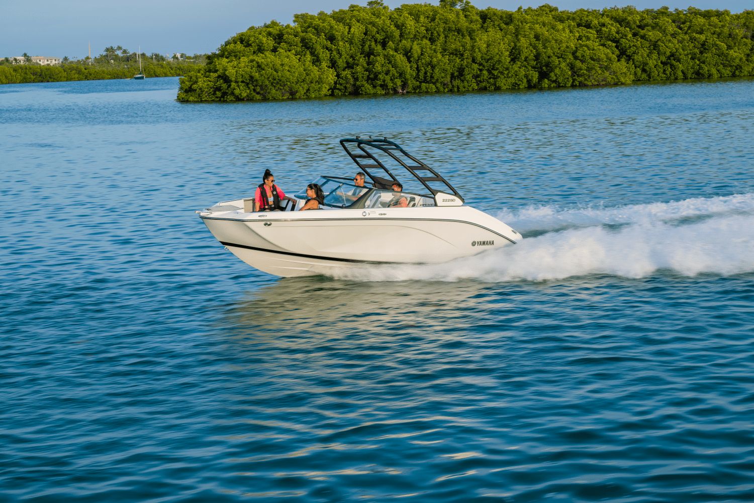 A Yamaha 222SD boat speeds across the water with three people on board.