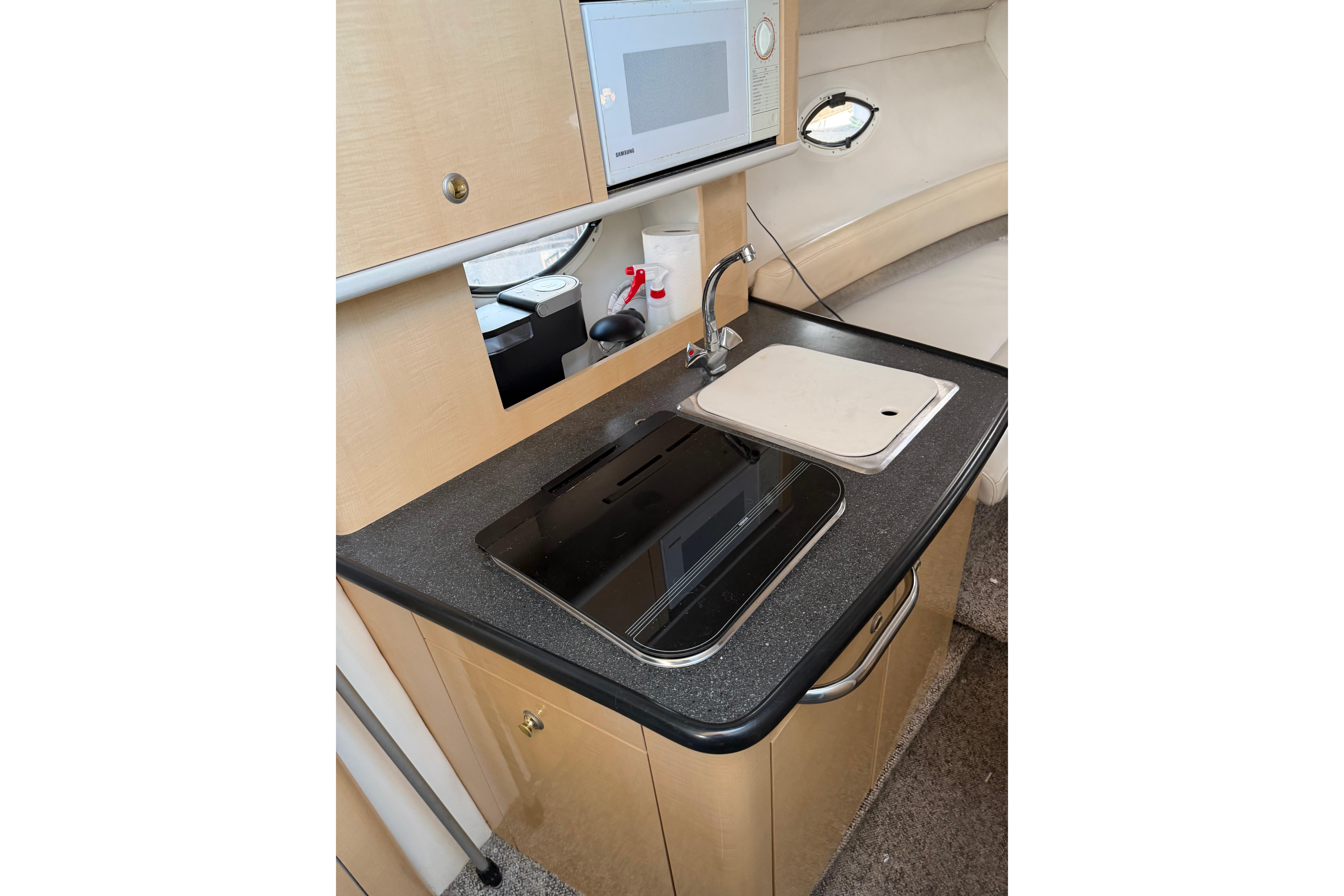 Compact kitchen area in a 2001 Maxum 2800 SCR boat, featuring a sink and stove.
