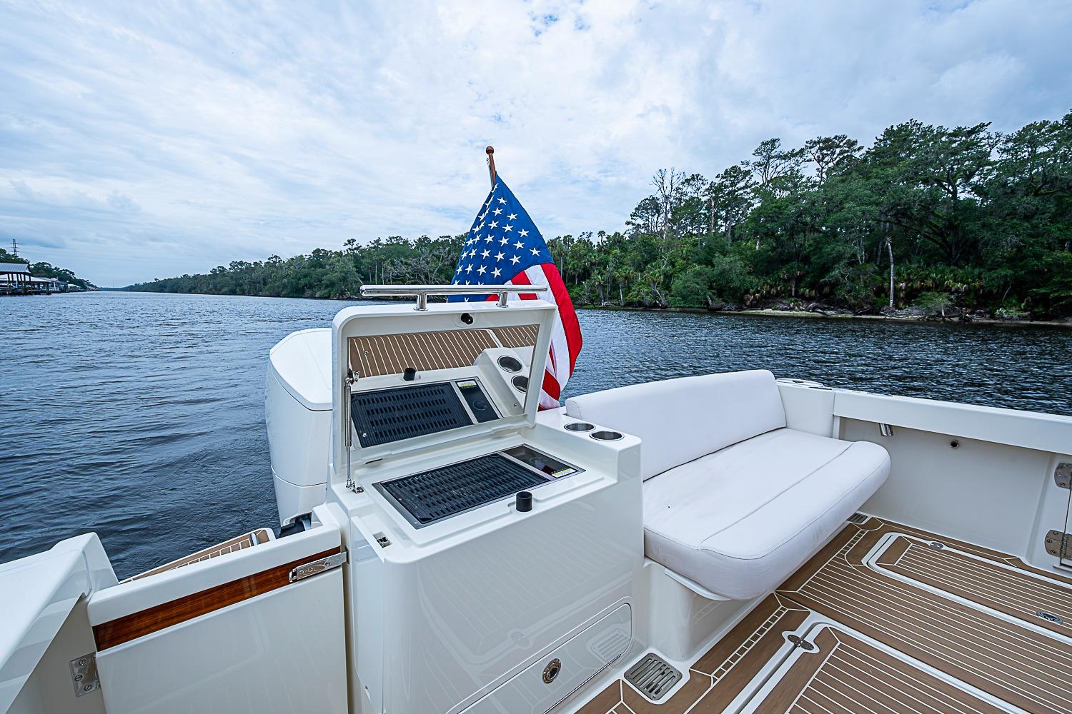 2023 Hinckley Sport Boat 40 X with American flag, spacious deck, and scenic river view.