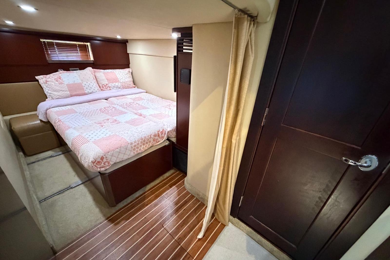 Luxurious cabin interior of 2006 Sea Ray 480 Sundancer with cozy bed and wooden accents.