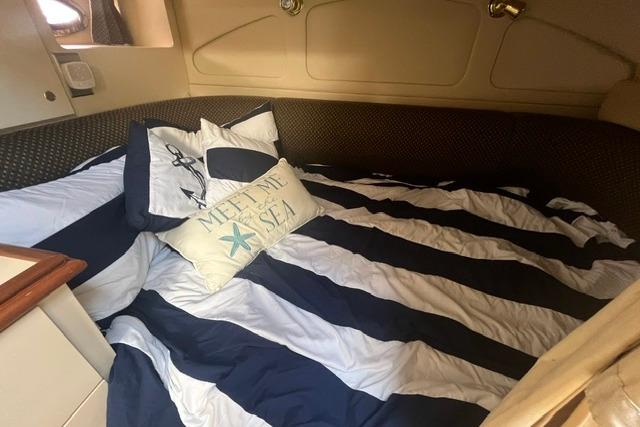 Cozy cabin interior of 2004 Cruisers Yachts 3372 Express with striped bedding and nautical decor.